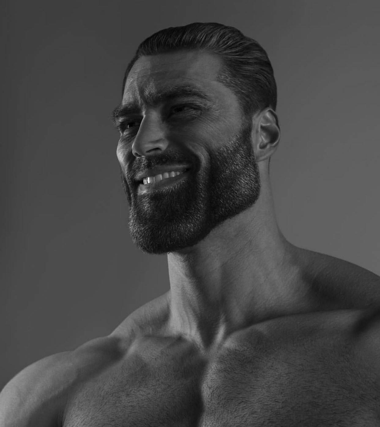 帥氣的Giga Chad 壁紙 — 一個肌肉發達、留著濃密鬍鬚的男人在清晰的黑白工作室肖像中自信地微笑。