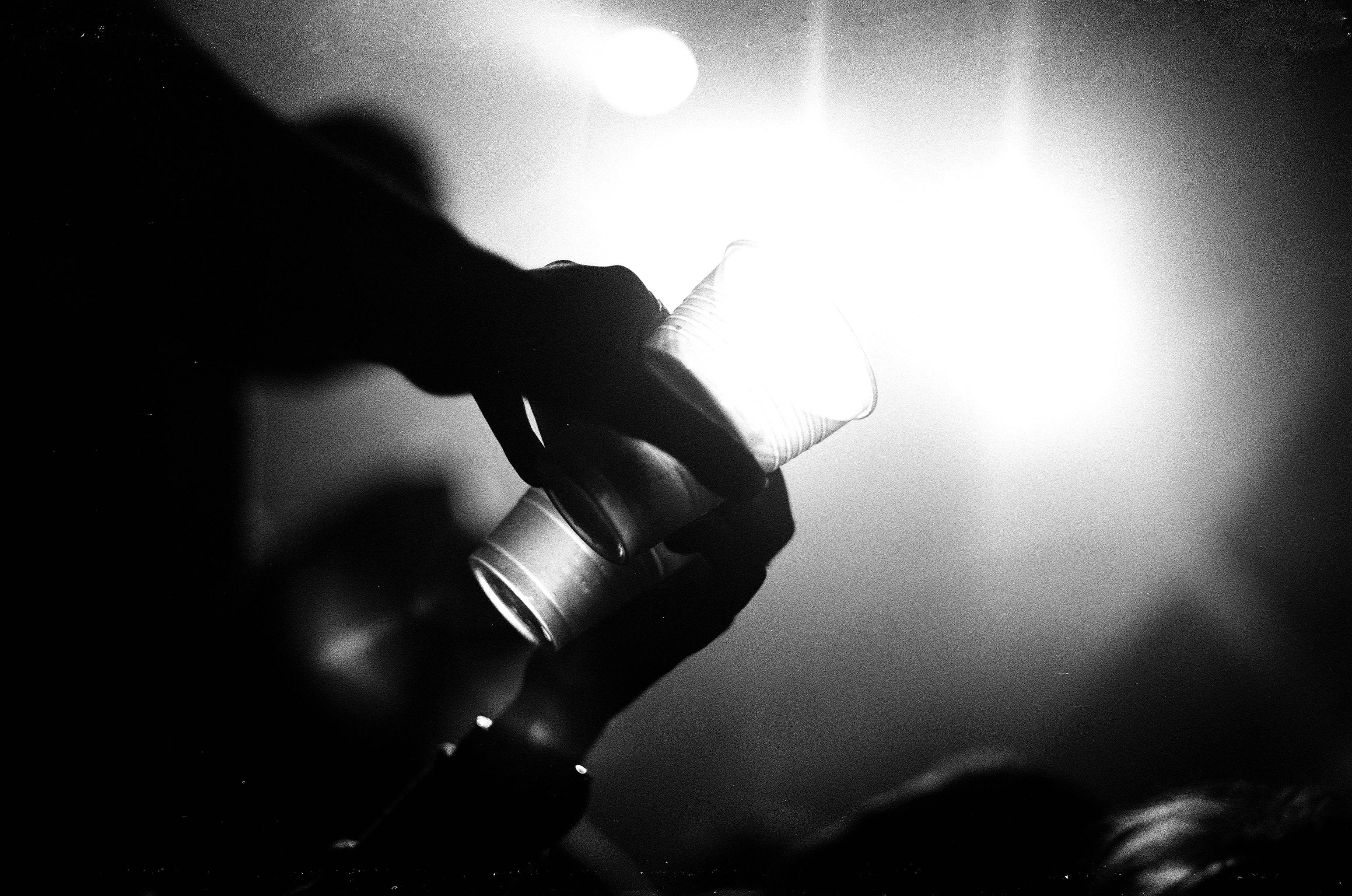 帶影子的燒杯 壁紙 — 一隻剪影手抓住發光的手電筒，背景明亮朦朧。