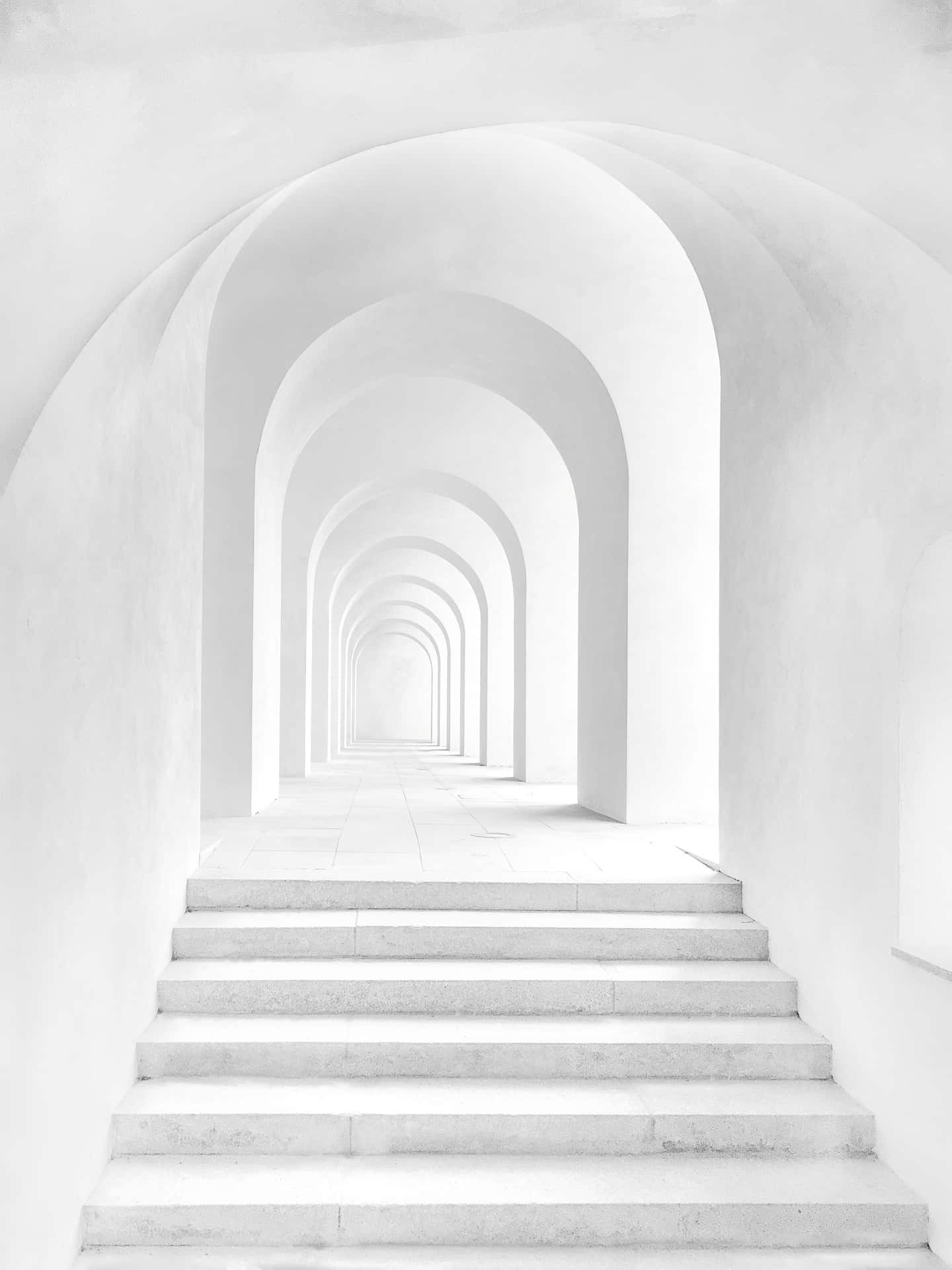 白色樓梯穿過極簡主義建築中的拱門隧道。