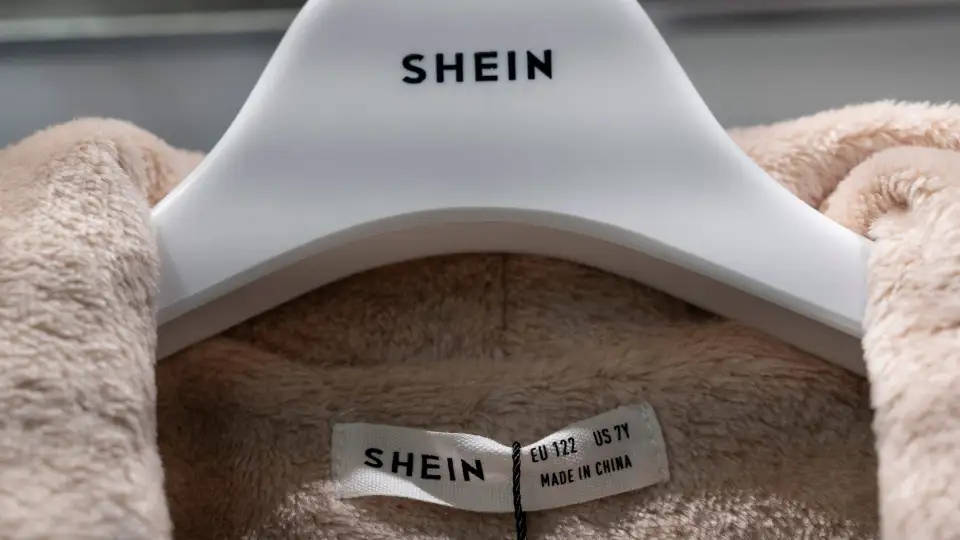 白色衣架上嘅米色絨毛衣物，附有SHEIN品牌標籤同尺寸標籤。