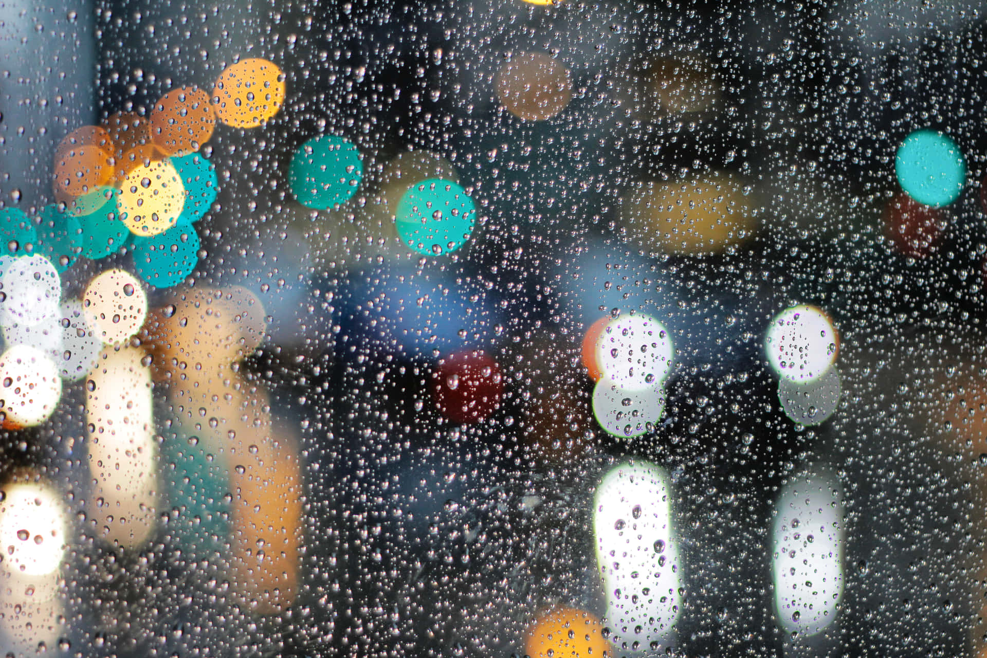 玻璃上的雨滴與模糊的城市燈光在散景中發光