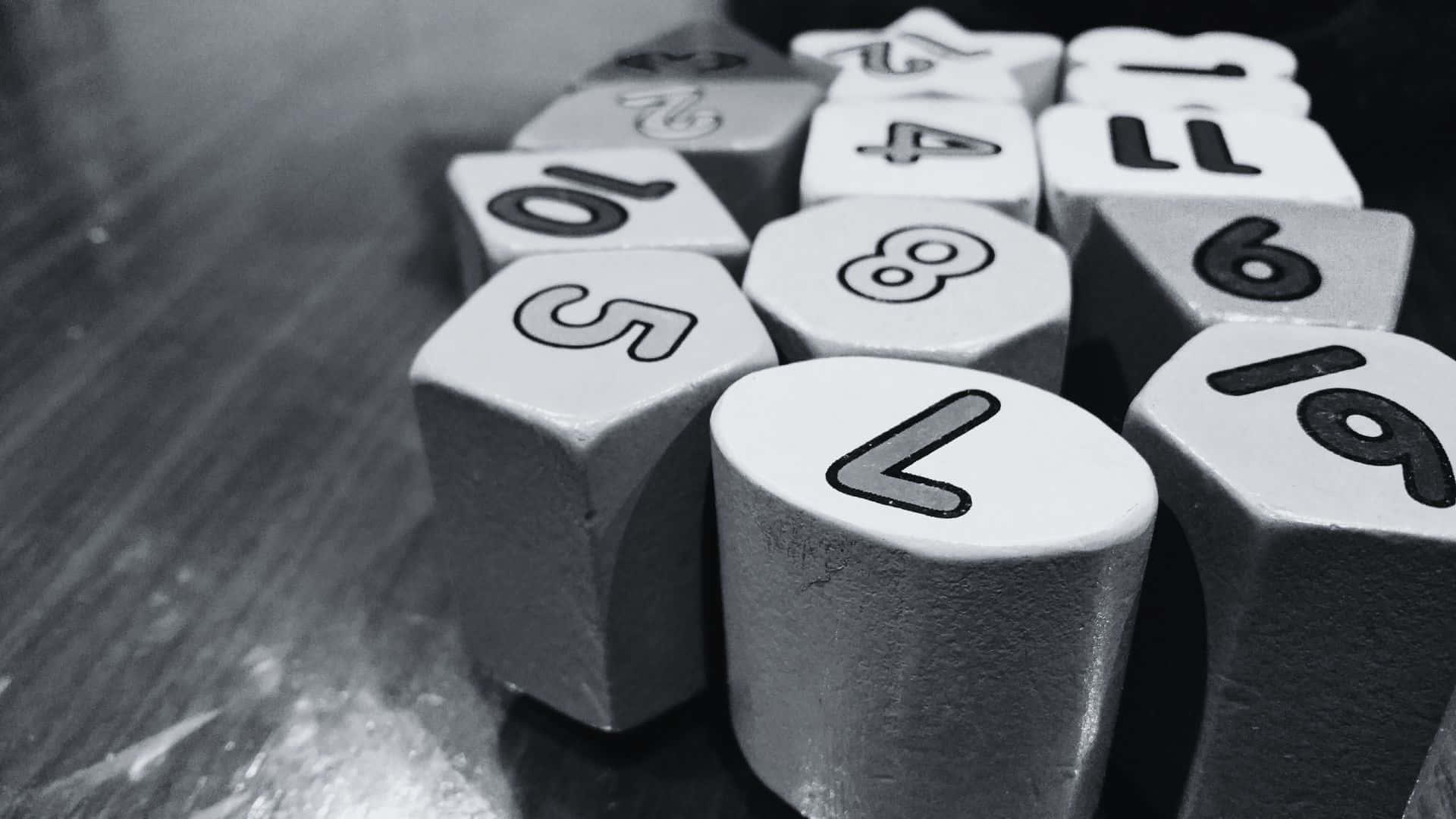 Black And White Number 桌布 壁紙 — 帶有數字的骰子近距離特寫，散亂地排列在反光表面上，呈單色調。