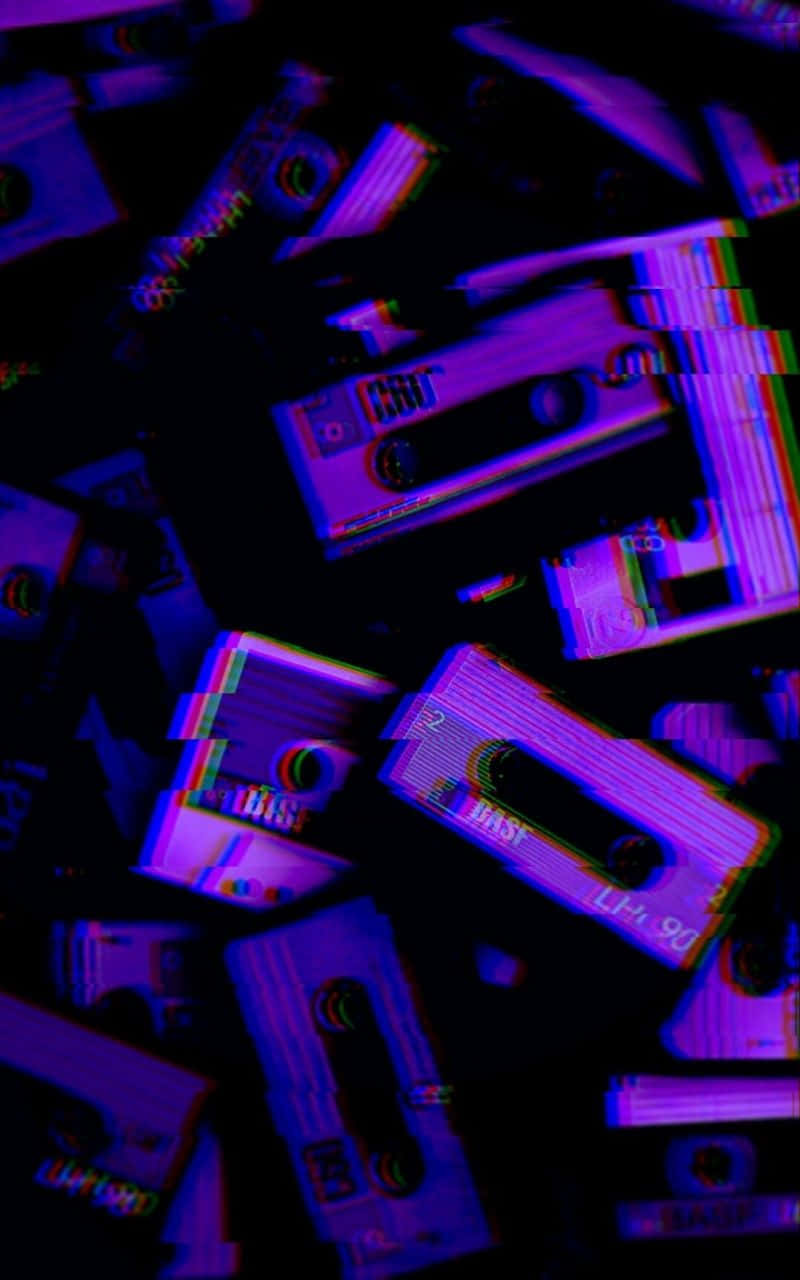 Aesthetic Grunge Phone 桌布 壁紙 — 帶有數碼失真效果的紫色和藍色卡式錄音帶散落在黑暗中。