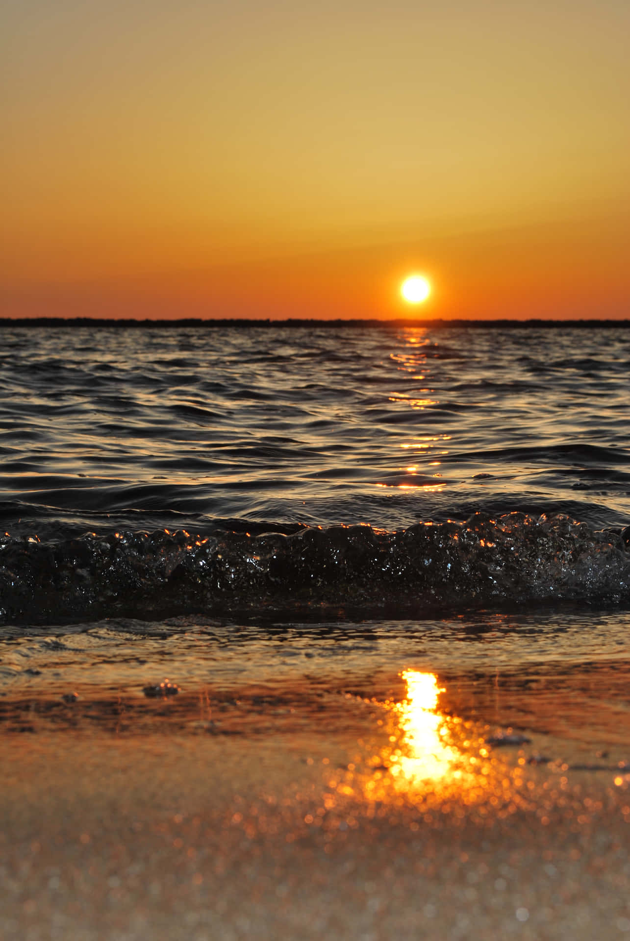 夕陽映照海洋，海浪沖刷沙灘
