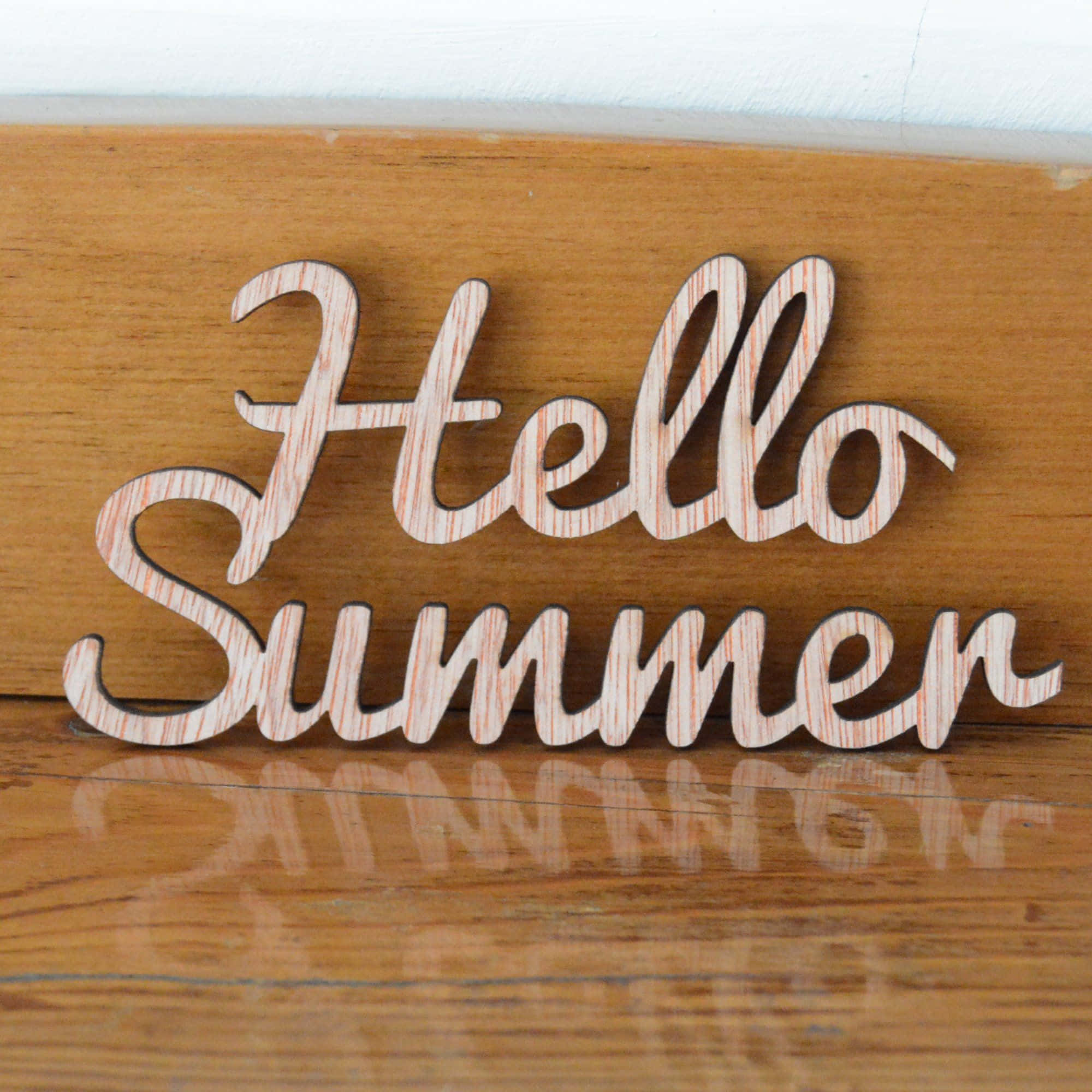 你好 桌布 壁紙 — 帶有條紋紋理的木製 'Hello Summer' 字母放置在拋光木質表面上，投射出柔和的反光。