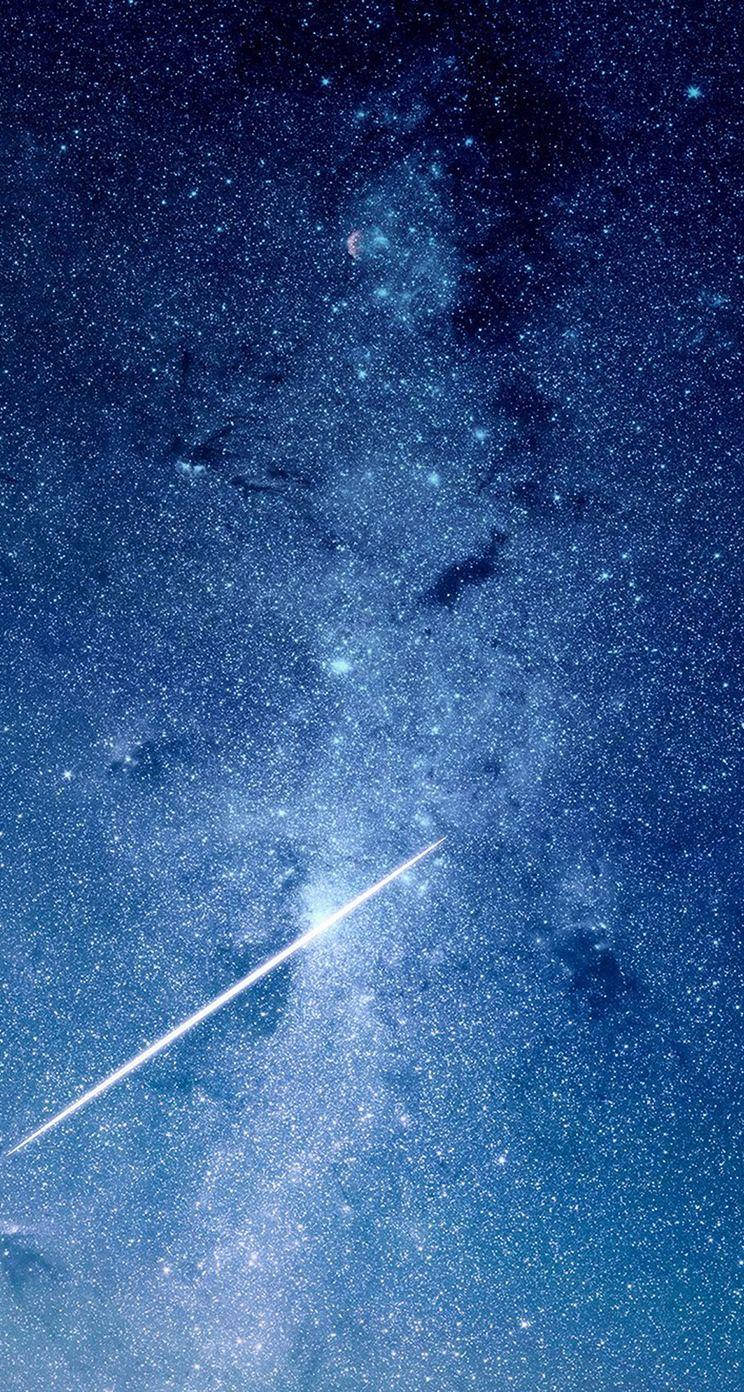 帶有流星的藍色星系 壁紙 — 一顆閃耀的流星劃過深藍色的星場，伴隨著發光的星雲和一彎新月，在宇宙的廣袤中。
