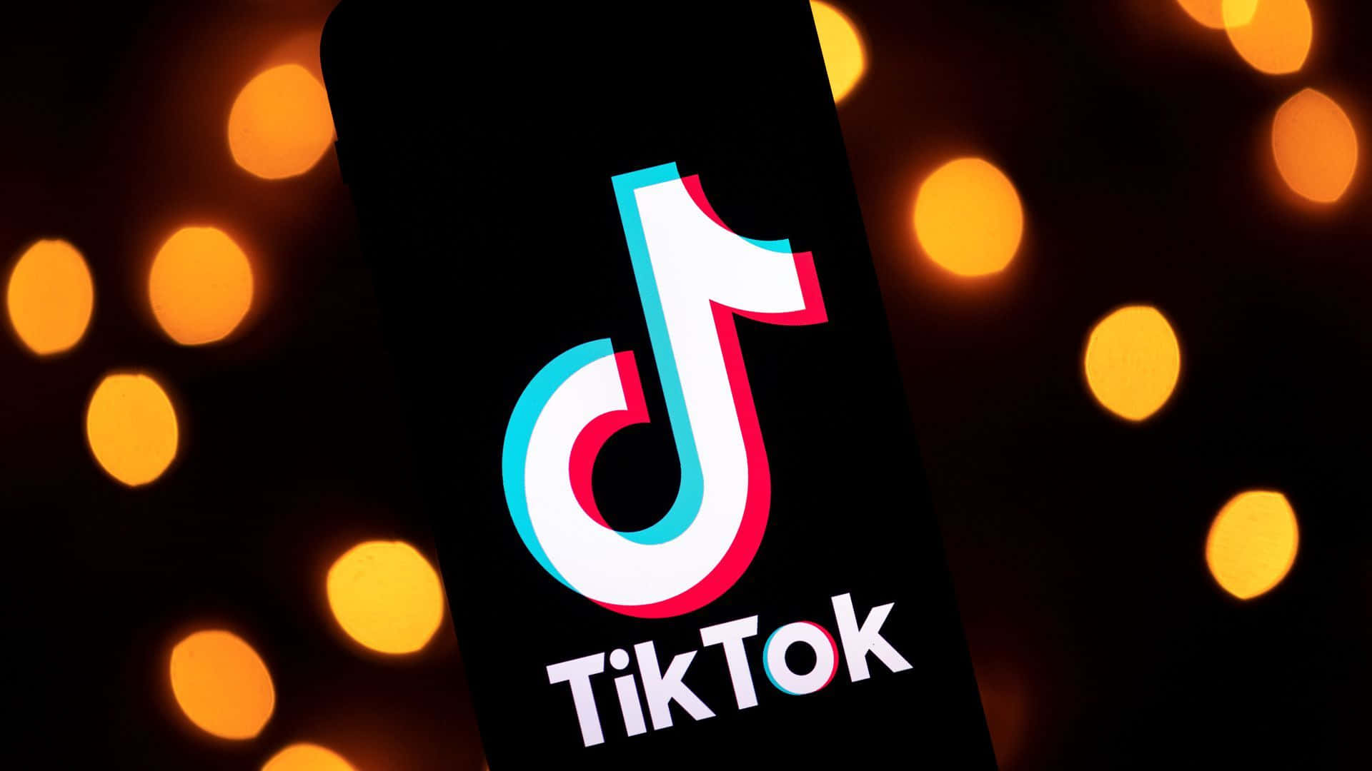 手機上顯示TikTok應用程式標誌，背景有發光的橙色燈光。