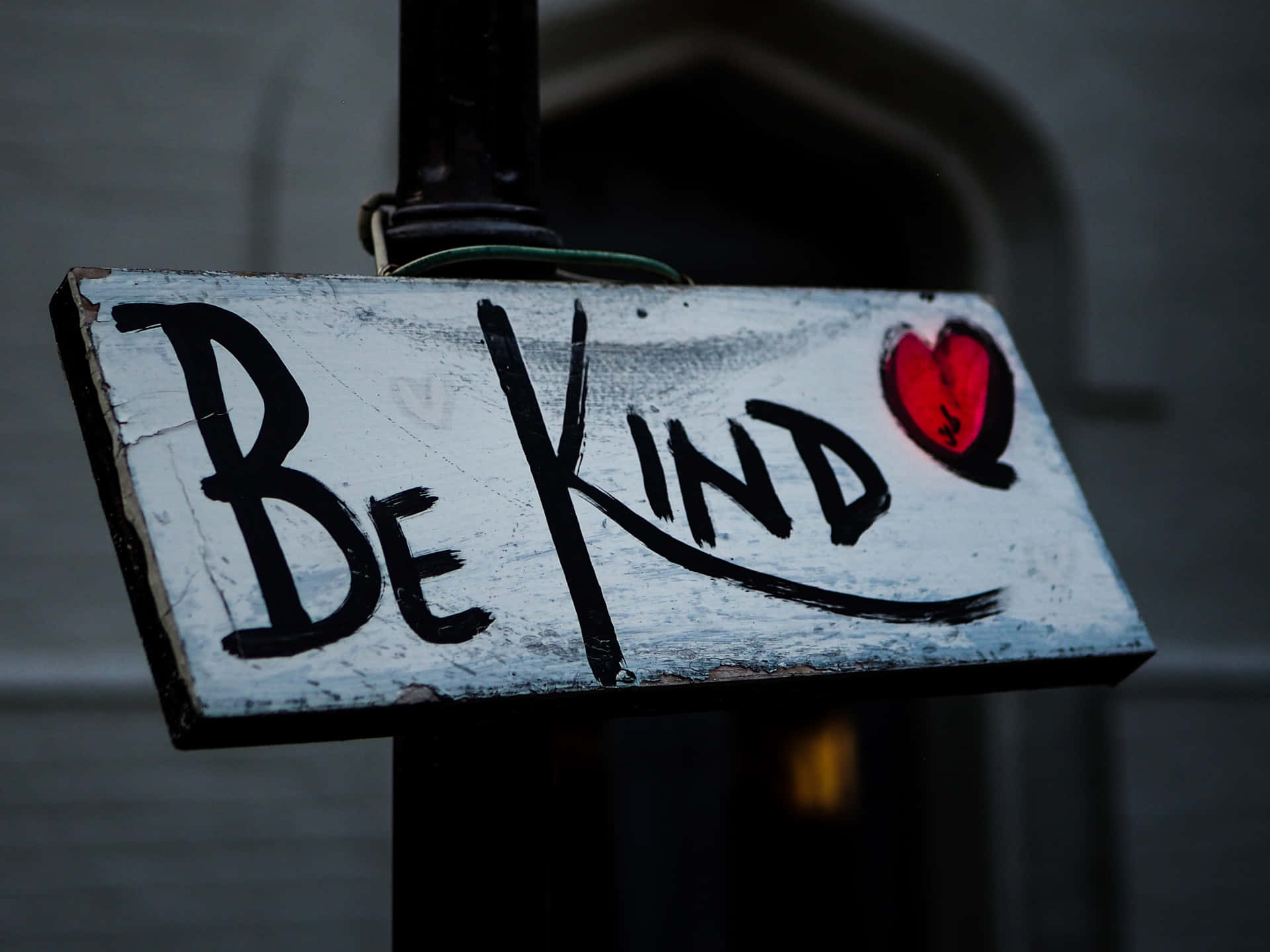 一個磨損的標牌，上面有「Be Kind」和一個紅色心形塗鴉。