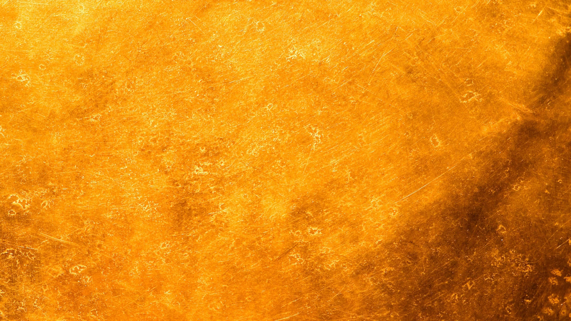 Yellow Grunge 桌布 壁紙 — 帶有細微刮痕和斑駁圖案的金色紋理表面，在整個畫面中溫暖地發光。