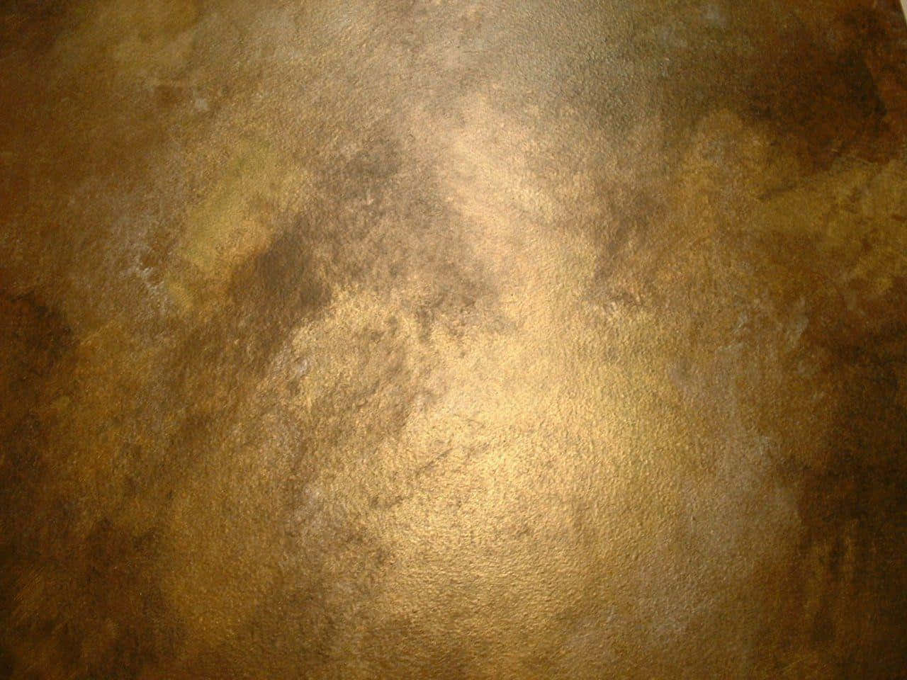 有紋理的金色和古銅色金屬表面的特寫，帶有反射高光。