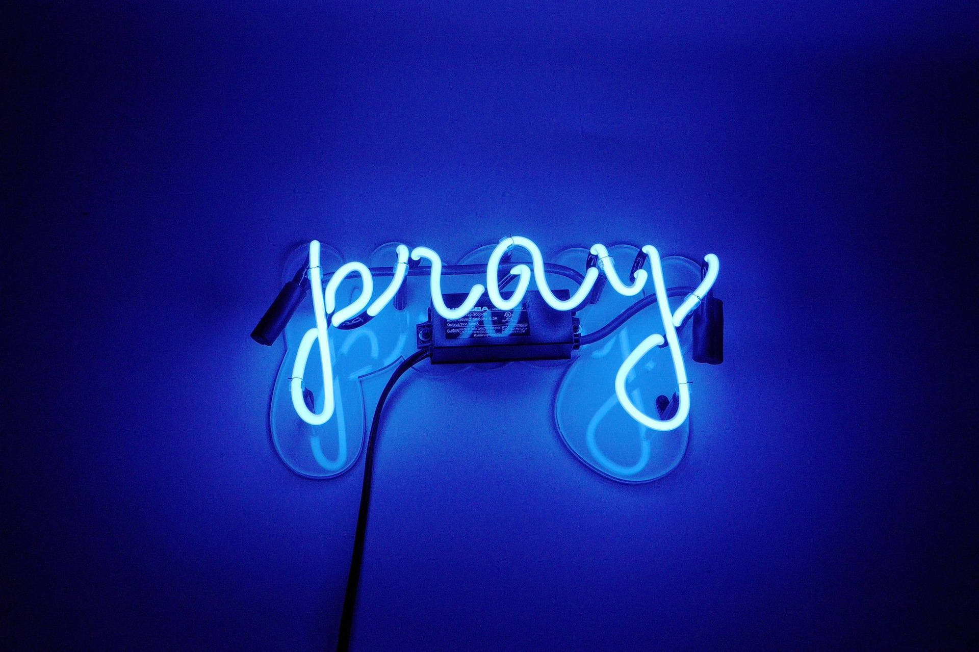 藍色霓虹燈牌，上面有「pray」字樣在暗牆上發光。 — 基督教 壁紙