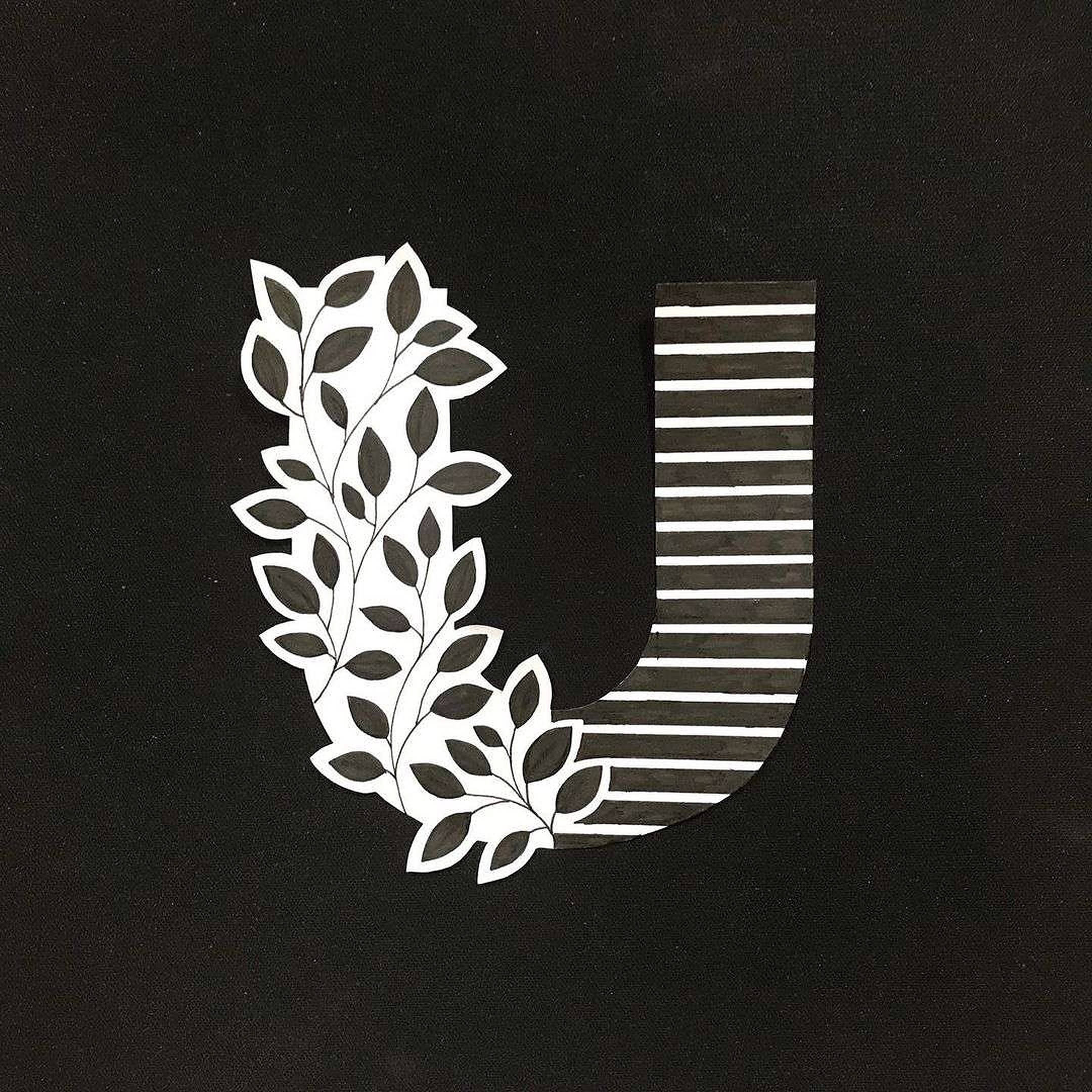 帶條紋的字母U 壁紙 — 一個風格化的字母U，一側有葉狀藤蔓，另一側有條紋圖案，置於黑色紋理背景上。