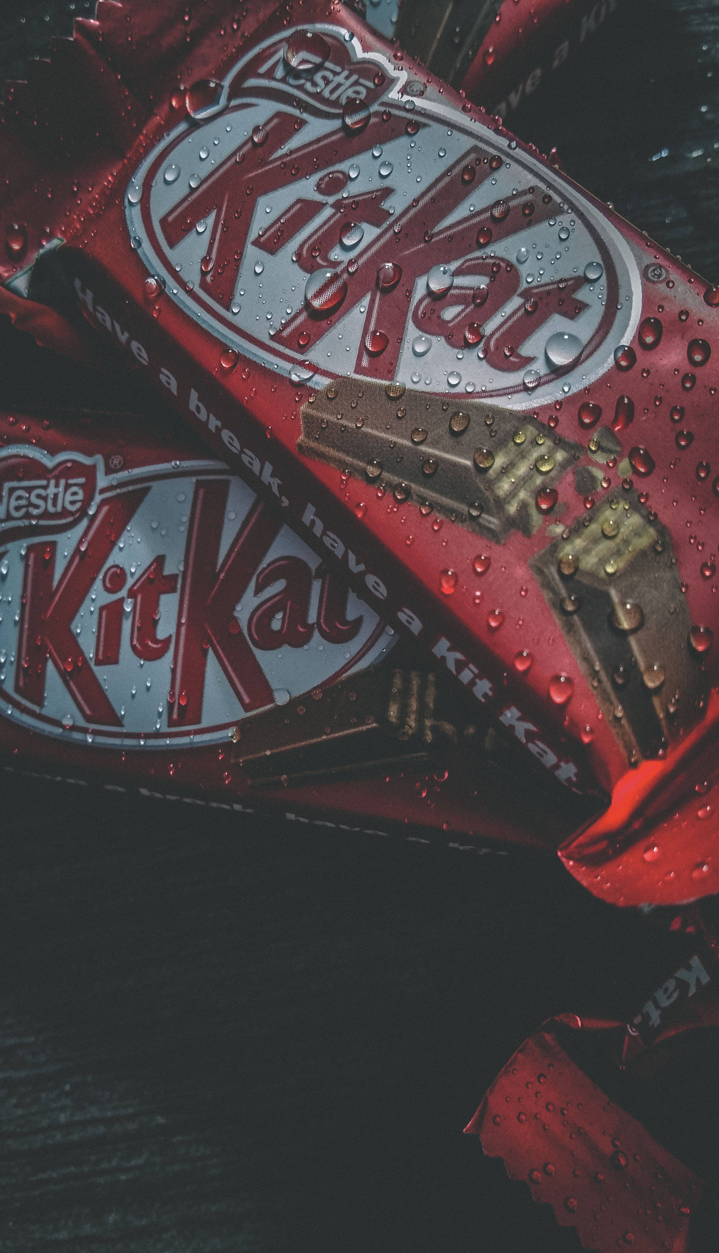 帶水珠的 Kit Kat 巧克力 壁紙 — 濕紅色KitKat朱古力棒的特寫，水珠在錫紙包裝上閃閃發光。