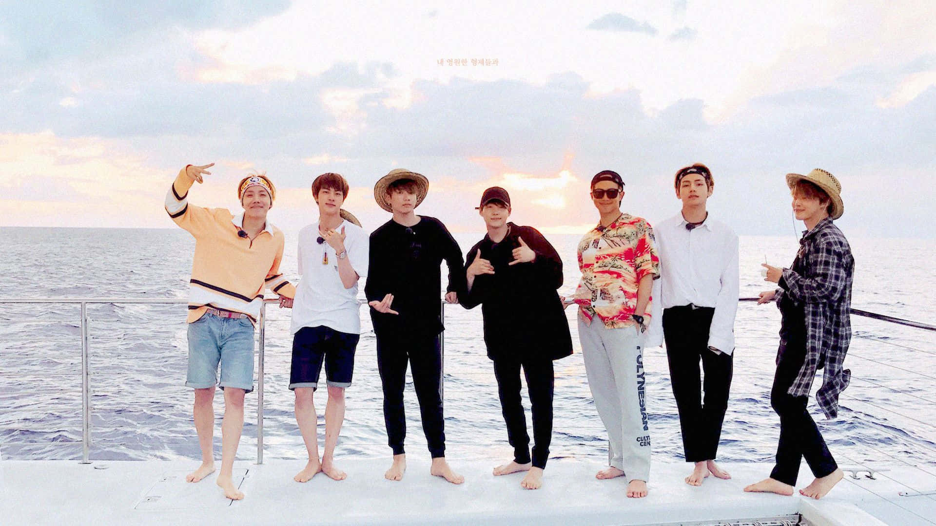 帶著你色彩繽紛的Mac前往#BTS ARMY 壁紙 — 七名身穿休閒夏季服裝的男子赤腳在船甲板上擺姿勢，背景是柔和的日落天空和寧靜的海洋。