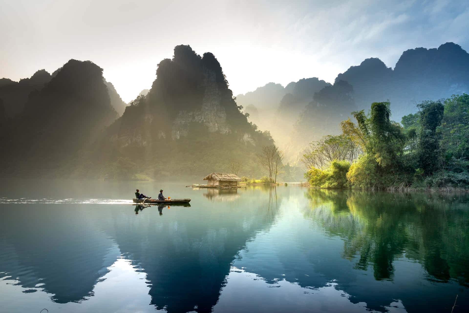 日出時分，兩人在霧氣瀰漫的湖上划船，四周環繞著高聳的山脈。