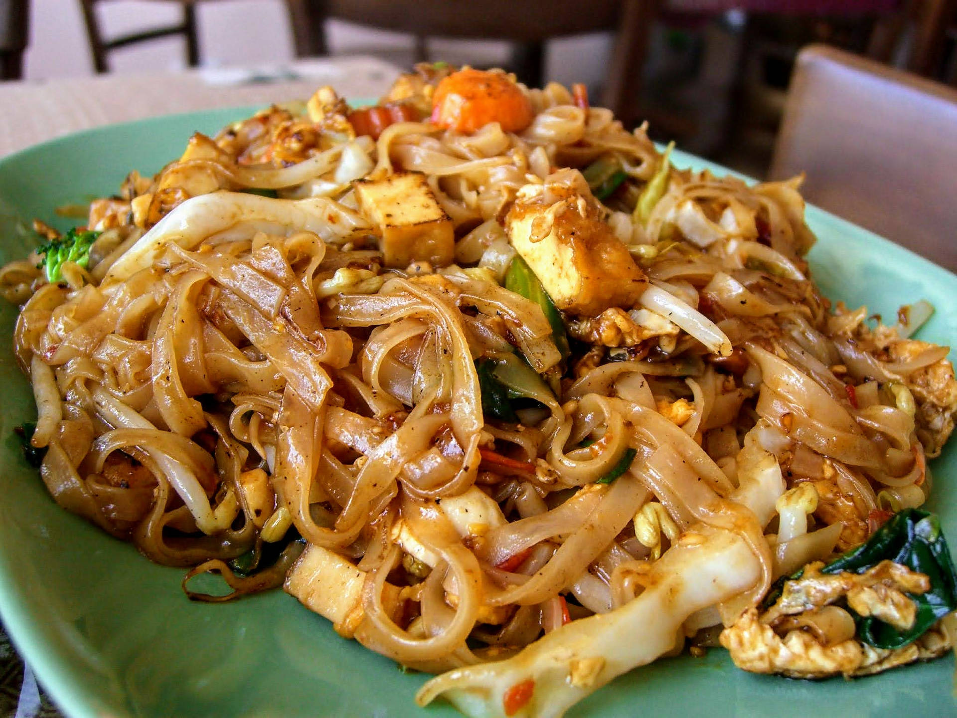 綠色碟上炒米粉配豆腐、西蘭花和紅蘿蔔。