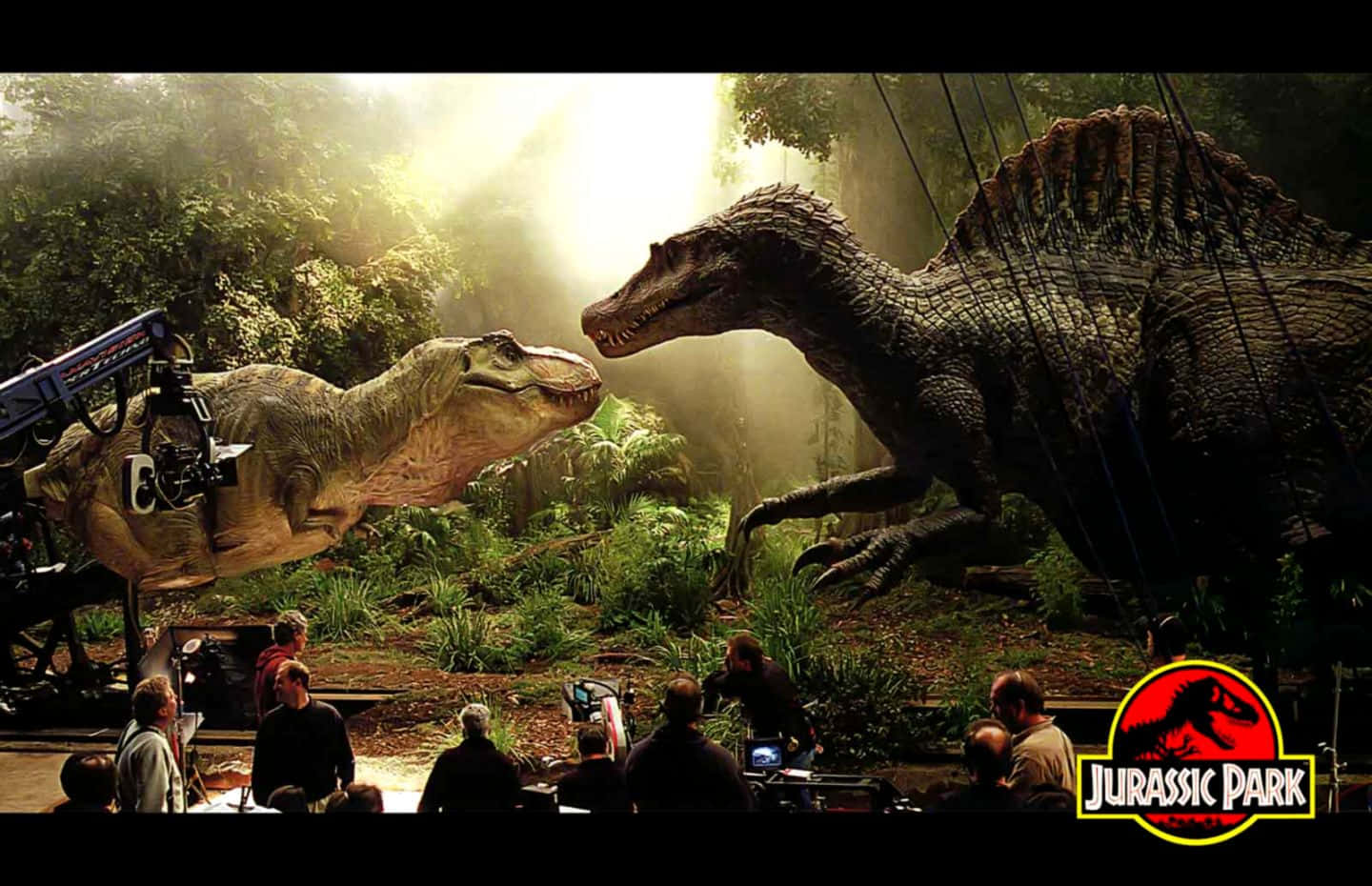 Jurassic World 桌布 壁紙 — 幕後拍攝鏡頭，顯示兩隻巨型恐龍在茂密叢林場景中，工作人員和設備清晰可見。