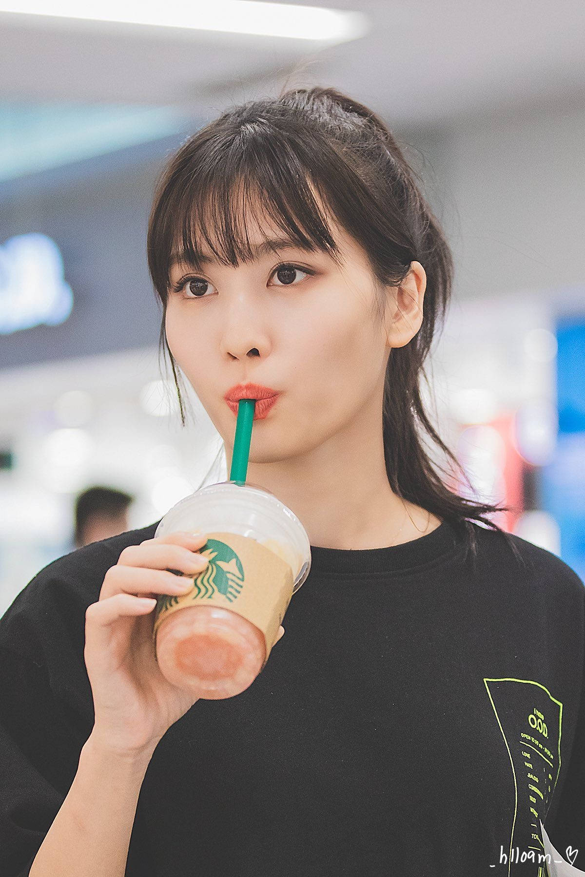 年輕女性用綠色吸管飲用粉紅色星巴克飲料。