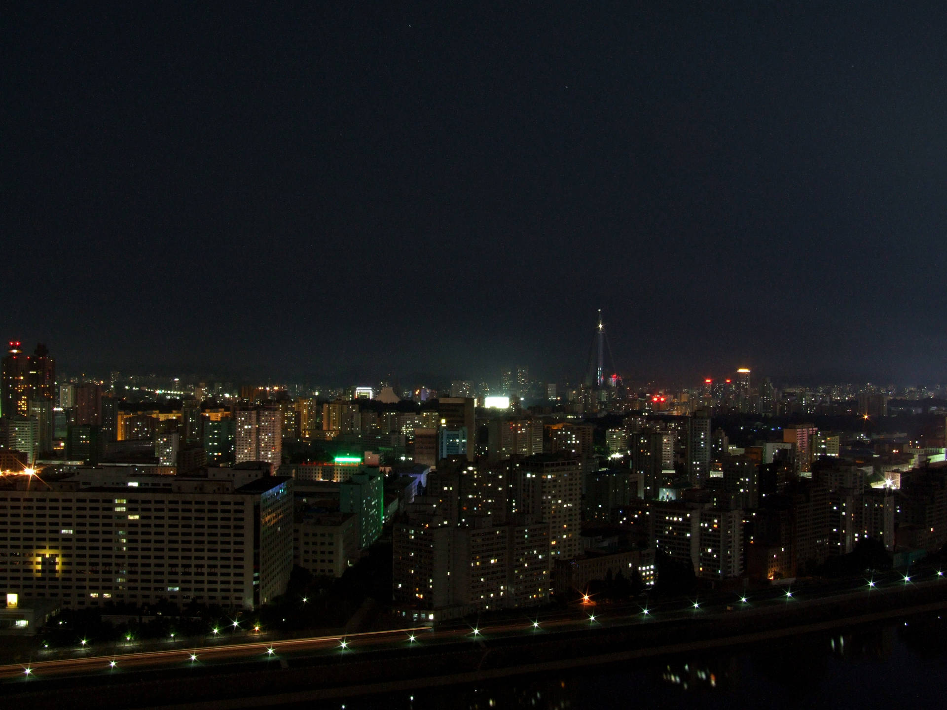城市夜景，有明亮的建築物和下方的河流。