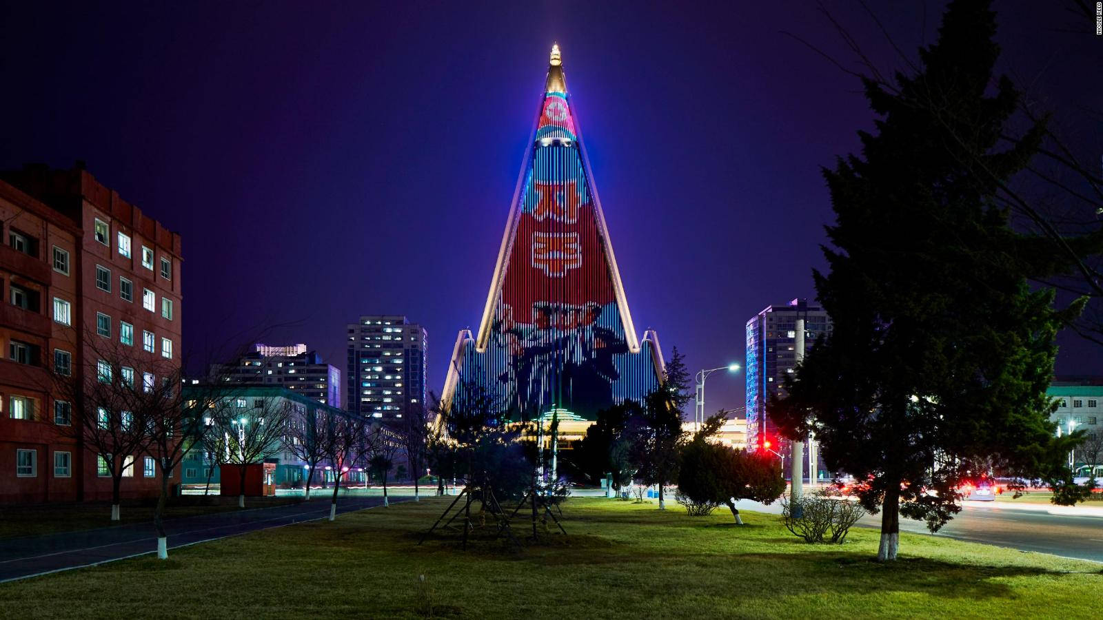 夜間城市環境中，一座明亮照明的金字塔建築帶有政治壁畫。