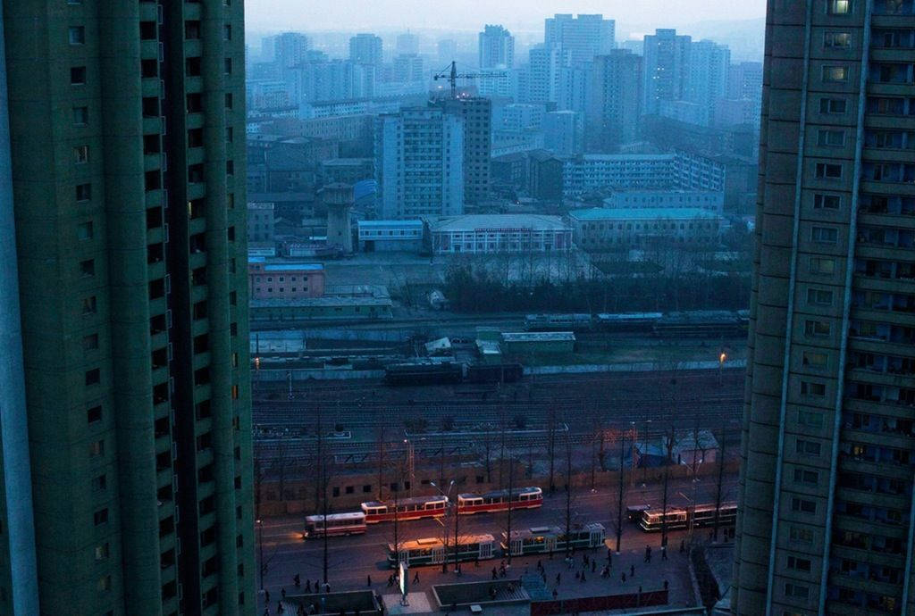 黃昏城市景觀，電車喺路軌上，被高樓大廈框住