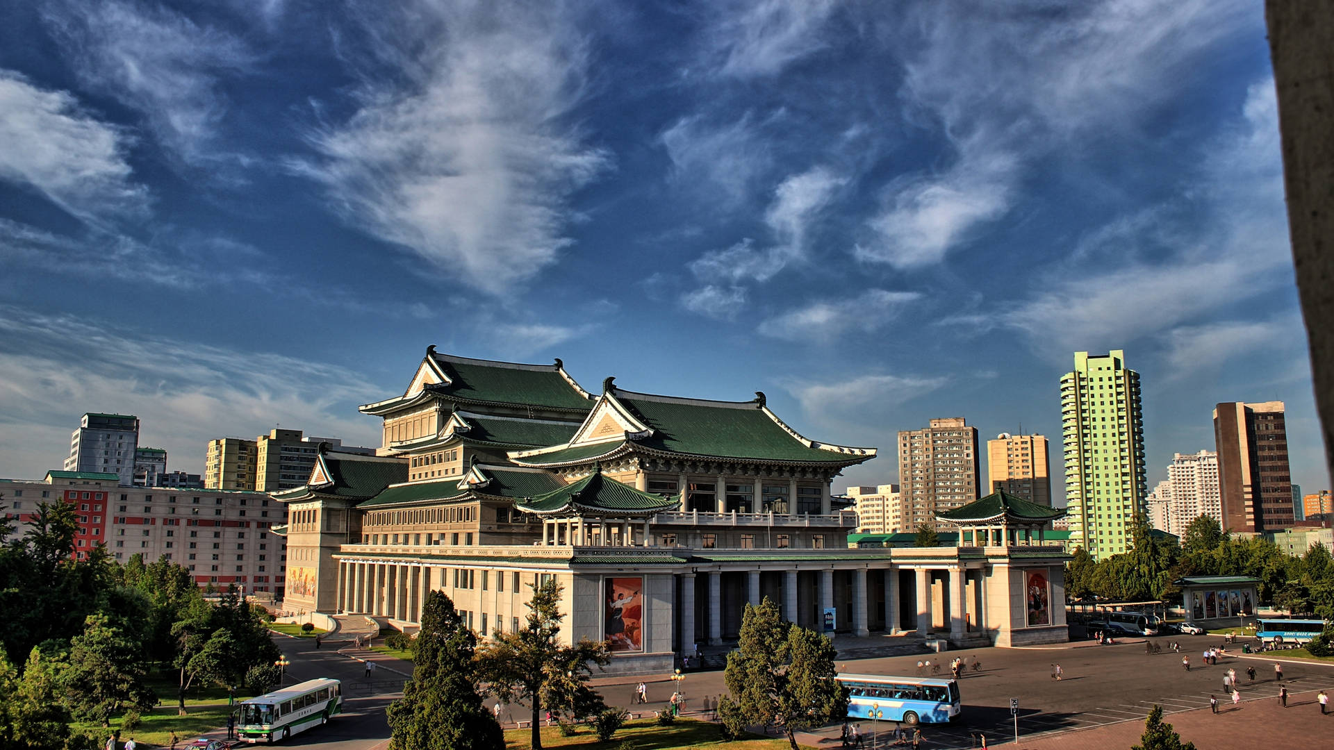 宏偉的傳統建築，綠色屋頂，在都市環境中，藍天白雲下。