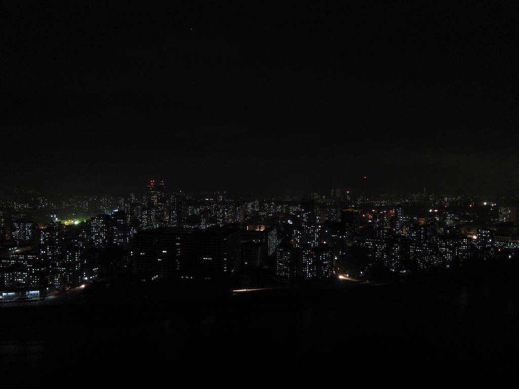 城市夜景，燈火通明的建築物映襯著黑暗的天空。
