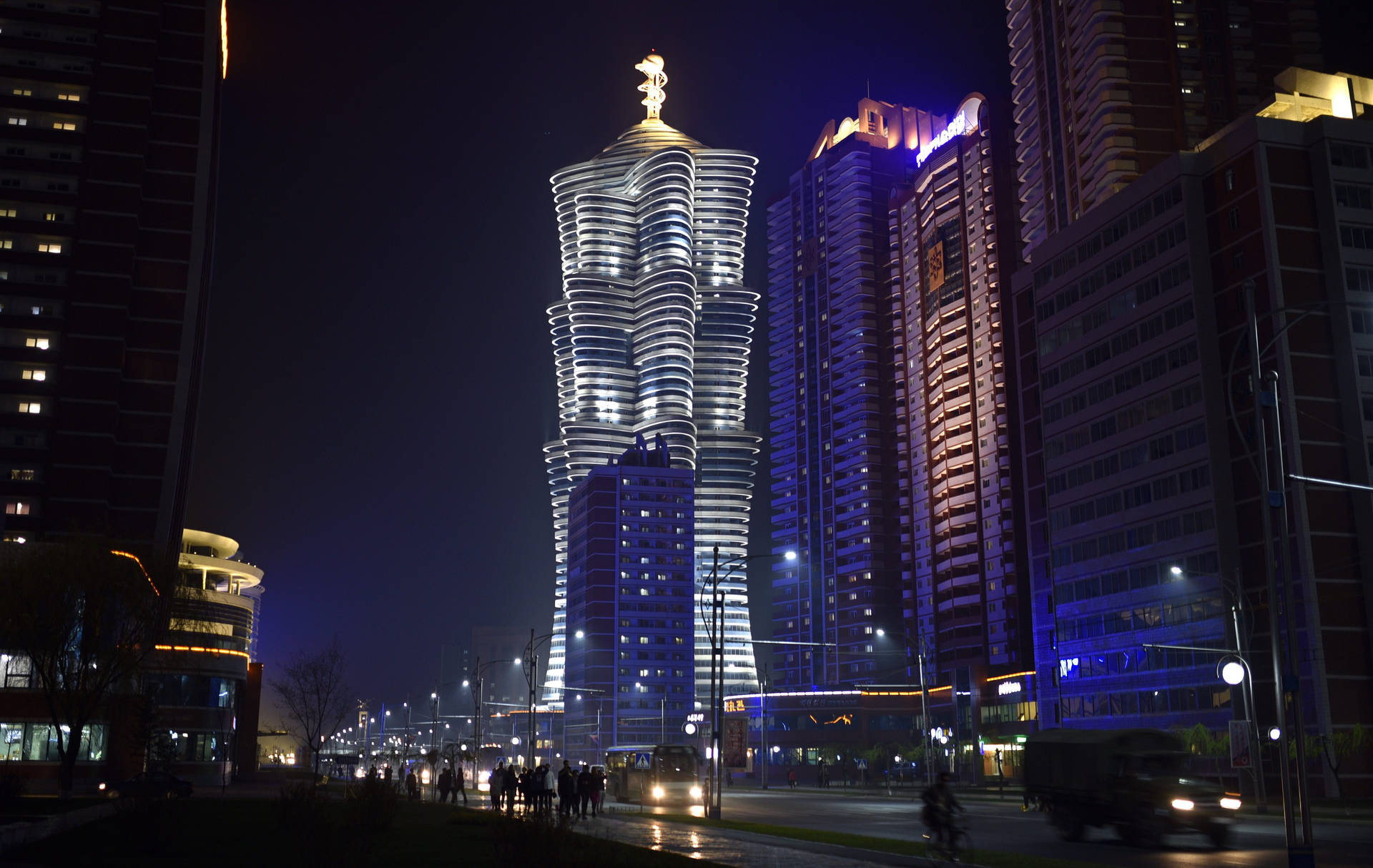 夜晚的城市景觀， featuring 一座頂部有金色雕像的發光摩天大樓。