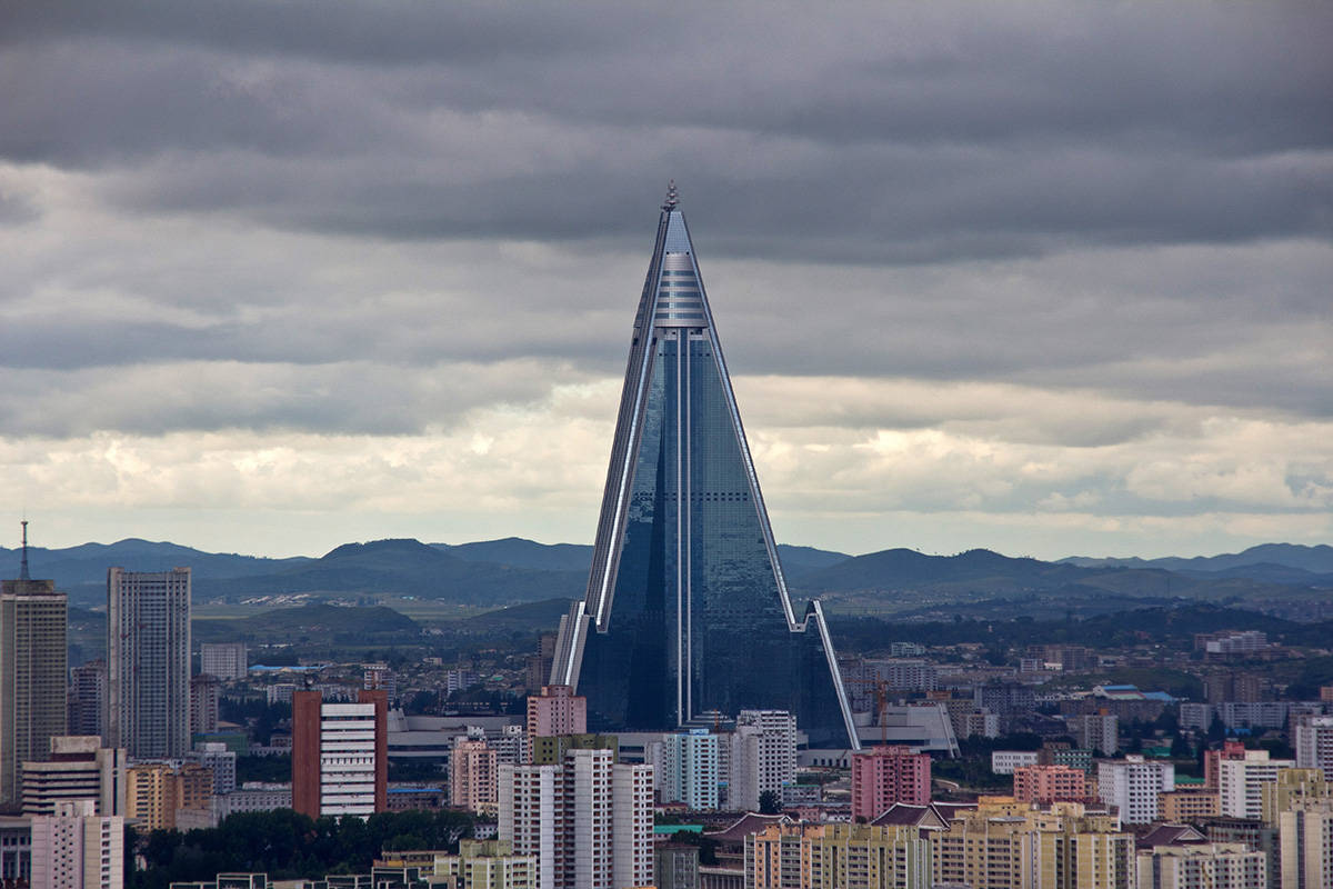 一座高大的玻璃金字塔建築在多雲的天空下矗立於城市之上。