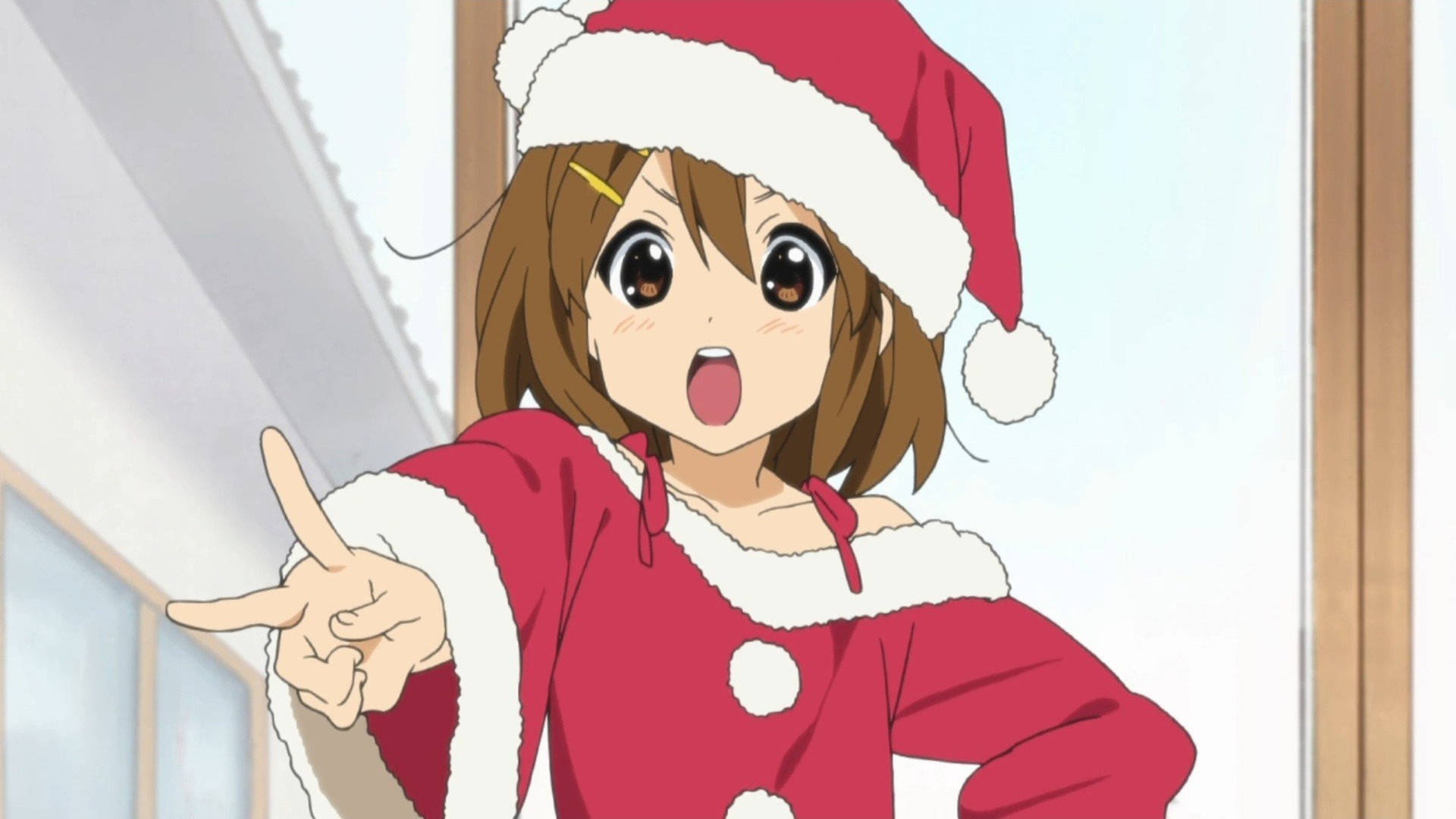 平澤唯 K-ON! 截圖 壁紙 — 一個開心的動漫女孩穿著紅色聖誕老人服裝，在室內睜大眼睛興奮地指著。