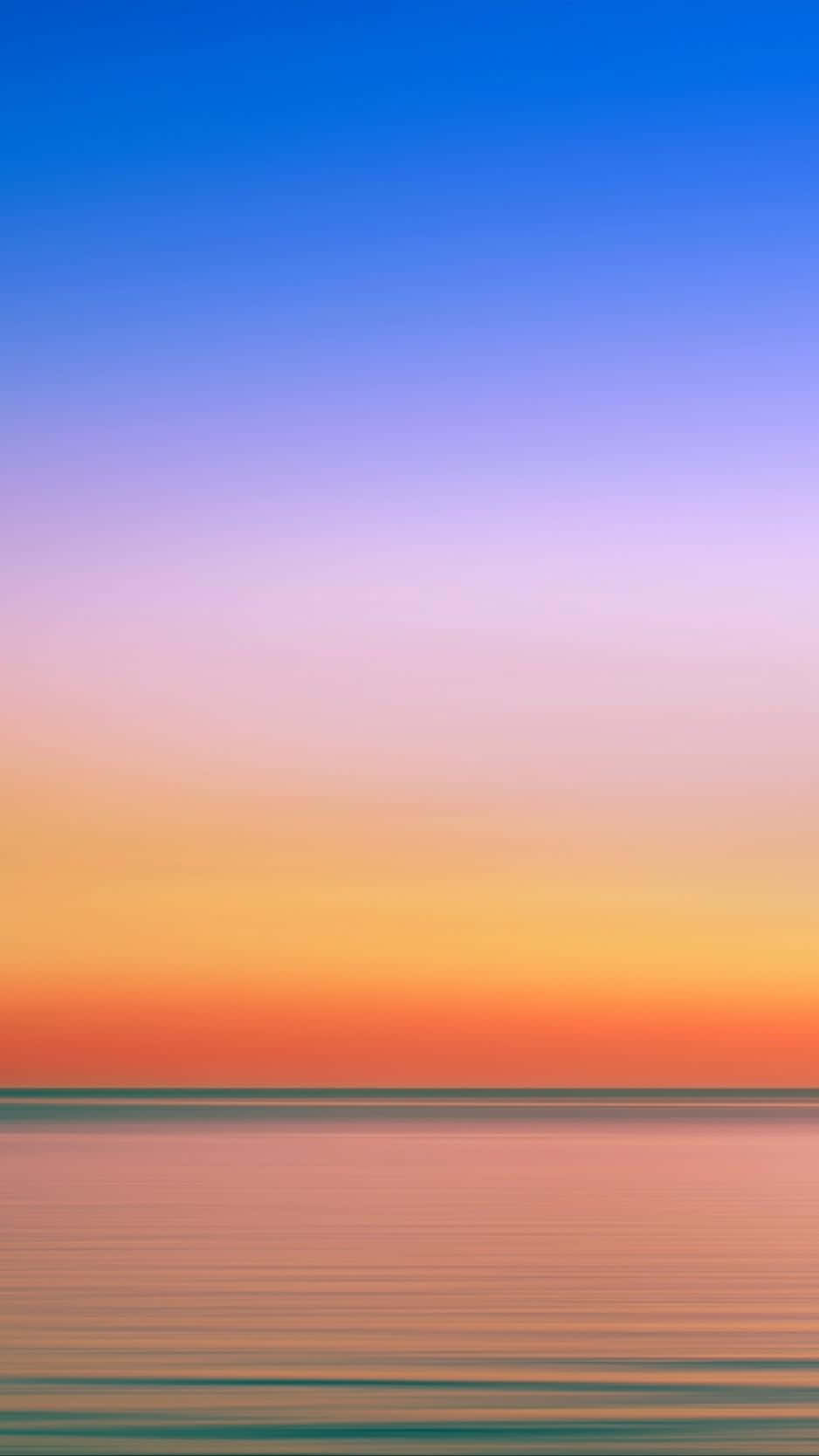 Minimalist Sunset 桌布 壁紙 — 平靜水面上從深藍色過渡到溫暖橙色和粉紅色調的寧靜日落漸變。
