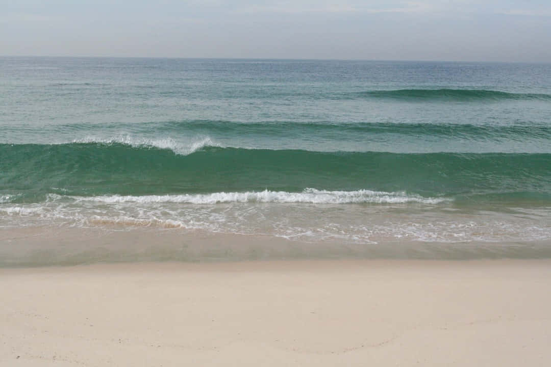 Beach Waves 桌布 壁紙 — 平靜的綠松石色海浪在陰天之下拍打著淡色沙灘。