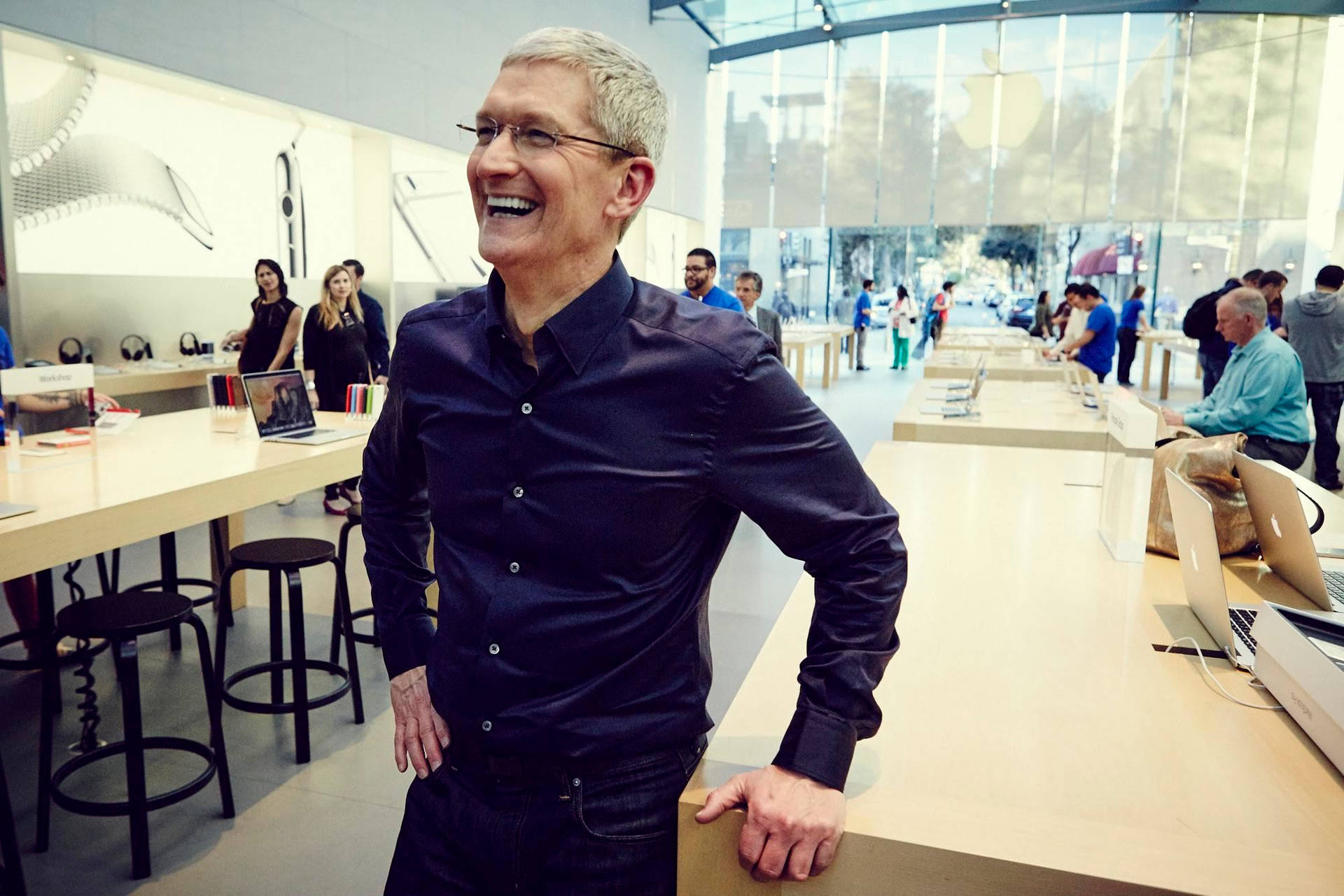 一個男人在Apple Store的櫃檯上靠著笑。