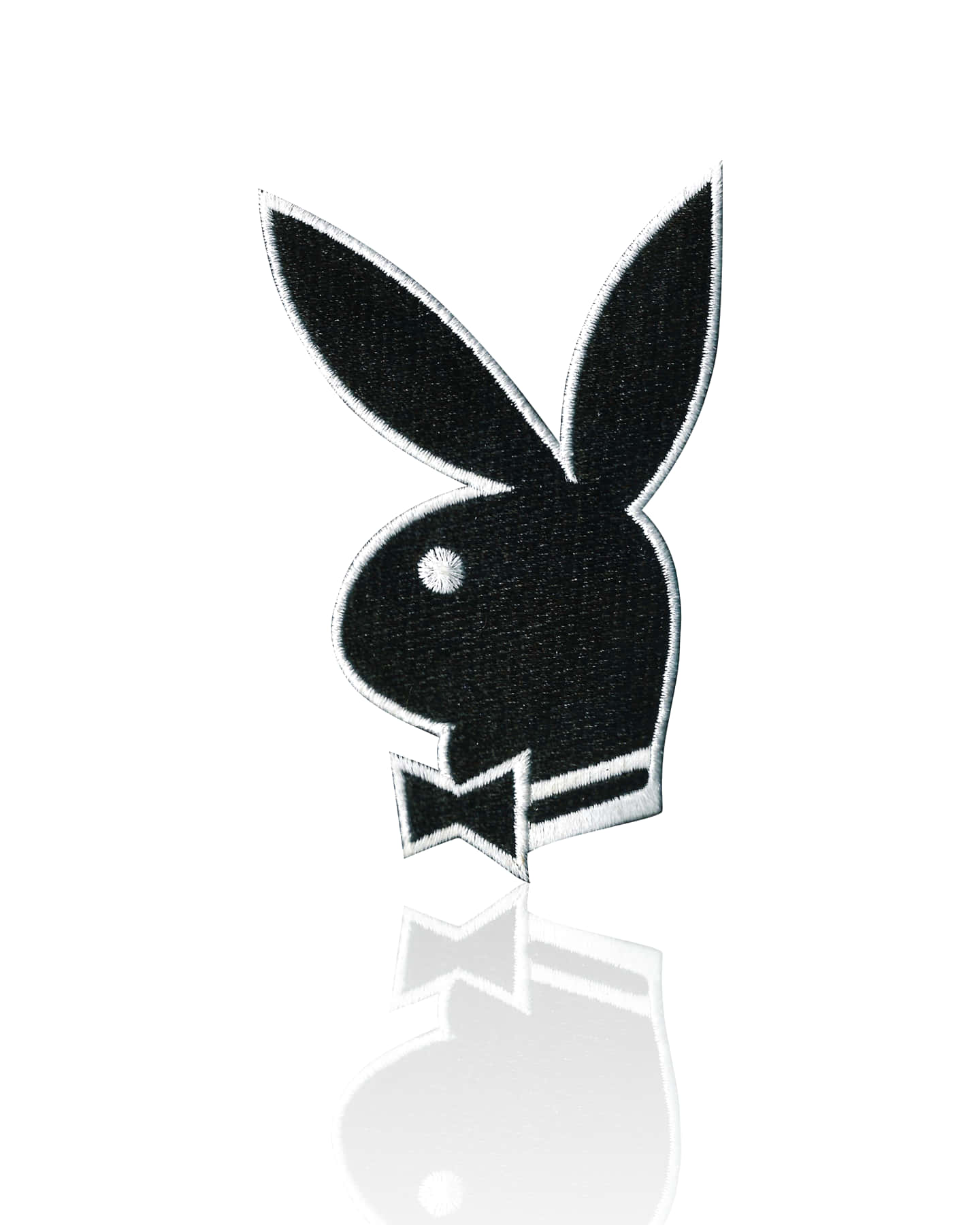 黑色刺繡Playboy兔子補丁，帶白色邊緣和蝴蝶結，置於反光表面。