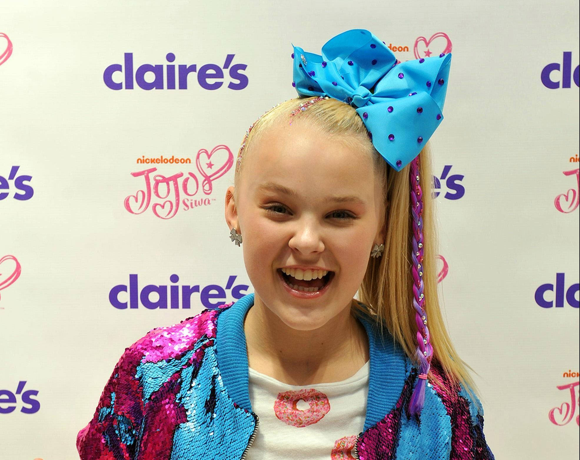 年輕 Jojo Siwa 為 Claire's 拍攝 壁紙 — JoJo Siwa 在 Claire's 活動中戴著巨大的藍色蝴蝶結和閃亮外套，洋溢著喜悅。