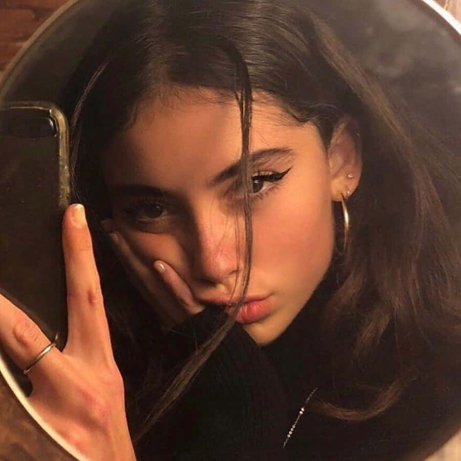 年輕女性在圓鏡中用手機自拍