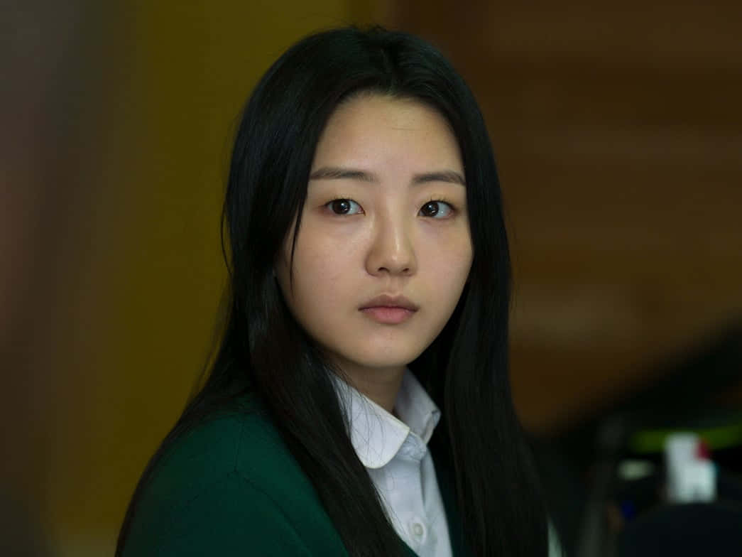 年輕女子身穿綠色襯衫，凝視著某物 壁紙