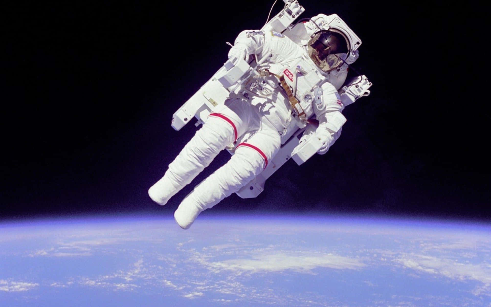 身穿白色太空衣的太空人漂浮在地球藍色曲線上方。