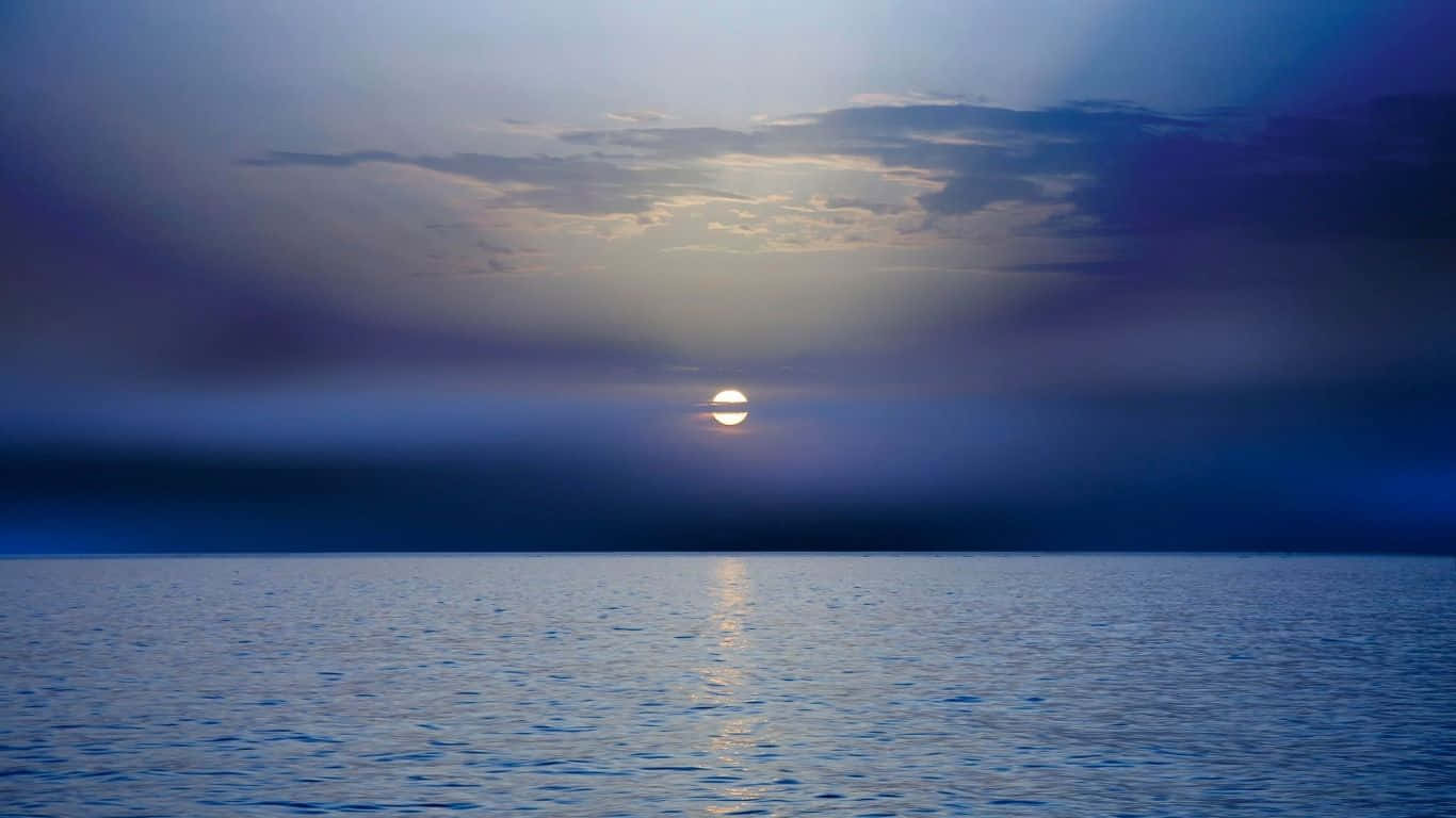 平靜海洋上的夕陽，帶有金色倒影和雲層密佈的天空