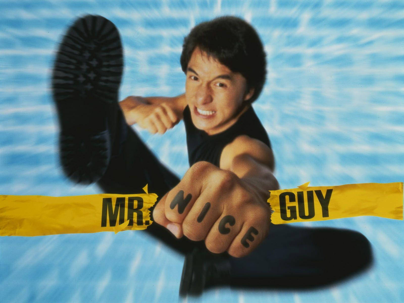 年輕成龍 壁紙 — 一個穿著黑色背心的男人微笑著向上踢，腳在藍色水波紋背景中可見，黃色膠帶上寫著mr nice guy橫跨他的拳頭。