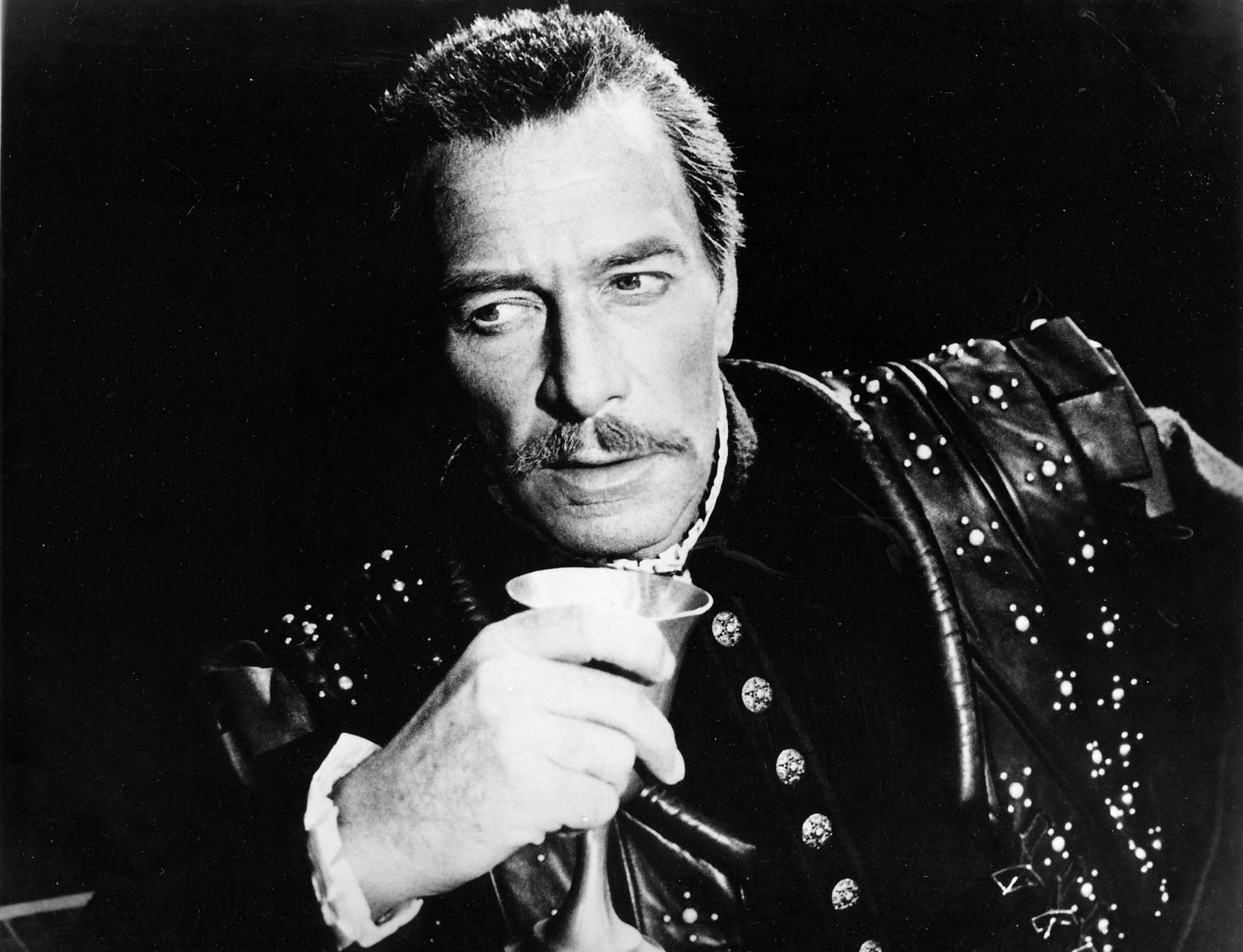 穿著歷史服裝的男人在戲劇性燈光下手持杯子。
