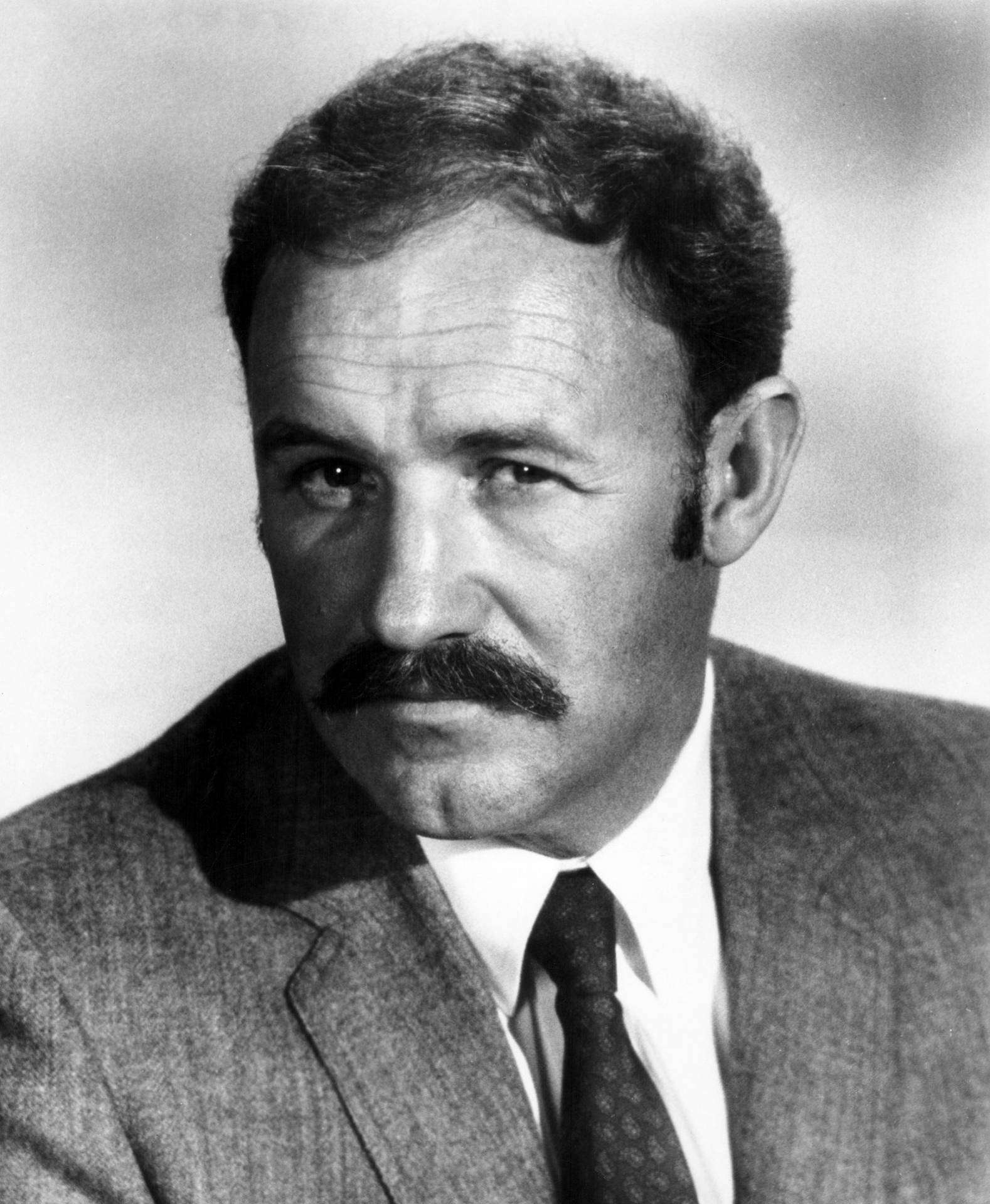 一個留鬍鬚的男人穿著西裝打領帶看著鏡頭。