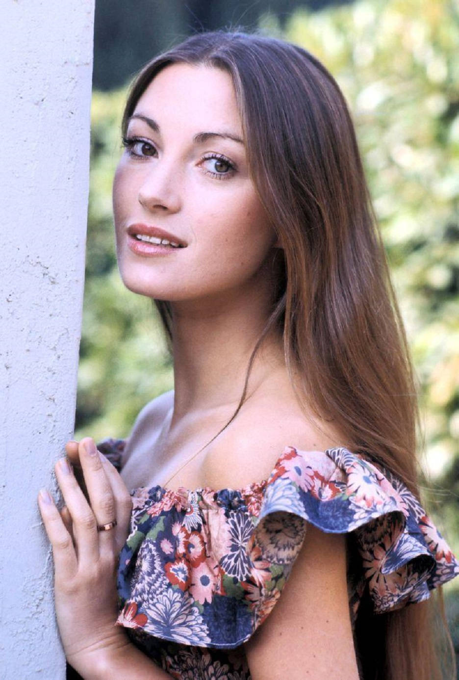 身穿花卉上衣的女性靠著戶外牆壁