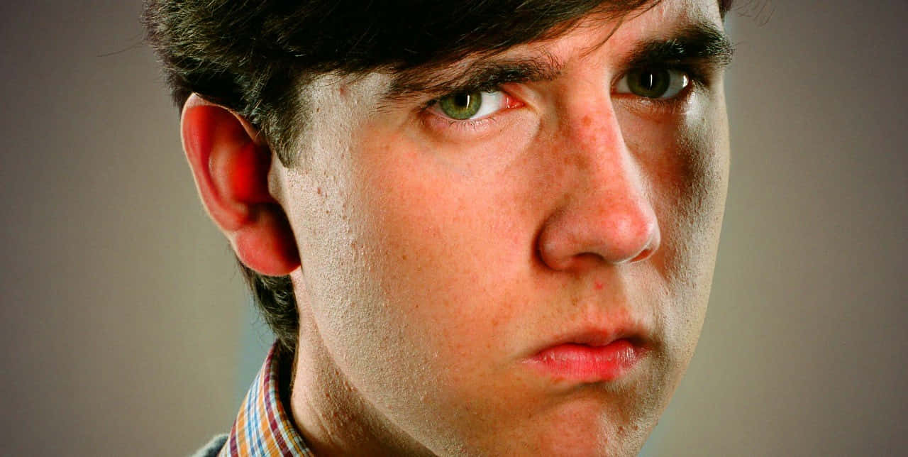 Neville Longbottom 桌布 壁紙 — 年輕男子嘅特寫肖像，佢有強烈嘅綠色眼睛同深色頭髮，直視鏡頭。