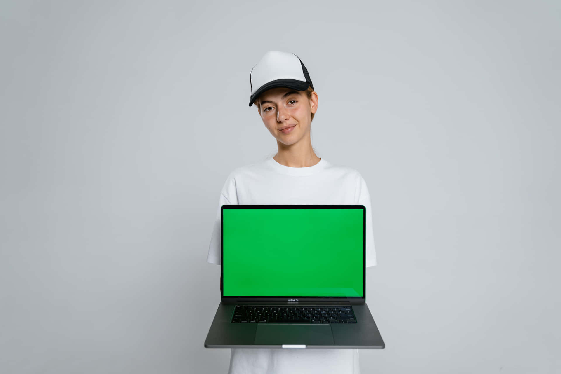 年輕女性在工作室環境中拿著帶有綠幕的筆記型電腦
