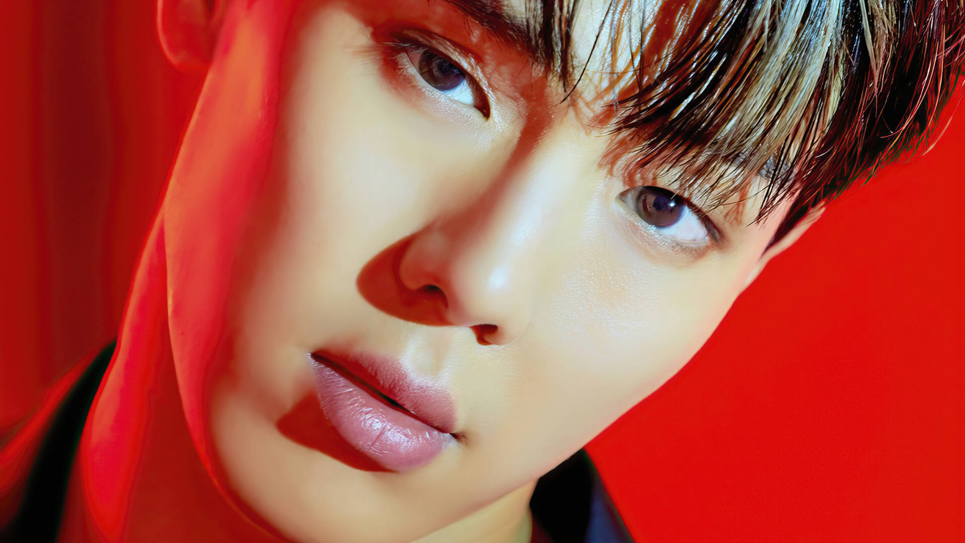 Monsta X Shownu 壁紙 — 年輕男子特寫肖像，眼神強烈，背景為鮮紅色，帶有戲劇性燈光。