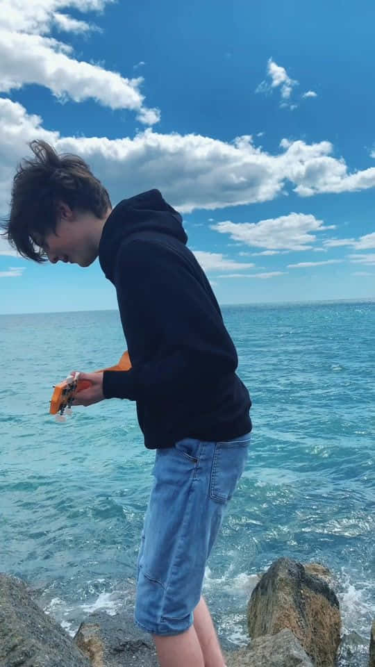 年輕男子站在海邊岩石上 壁紙