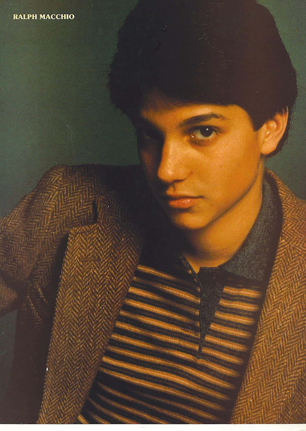 Ralph Macchio 桌布 壁紙 — 年輕的Ralph Macchio穿著人字紋西裝外套和條紋Polo衫，在柔和的綠色背景下專注地凝視。