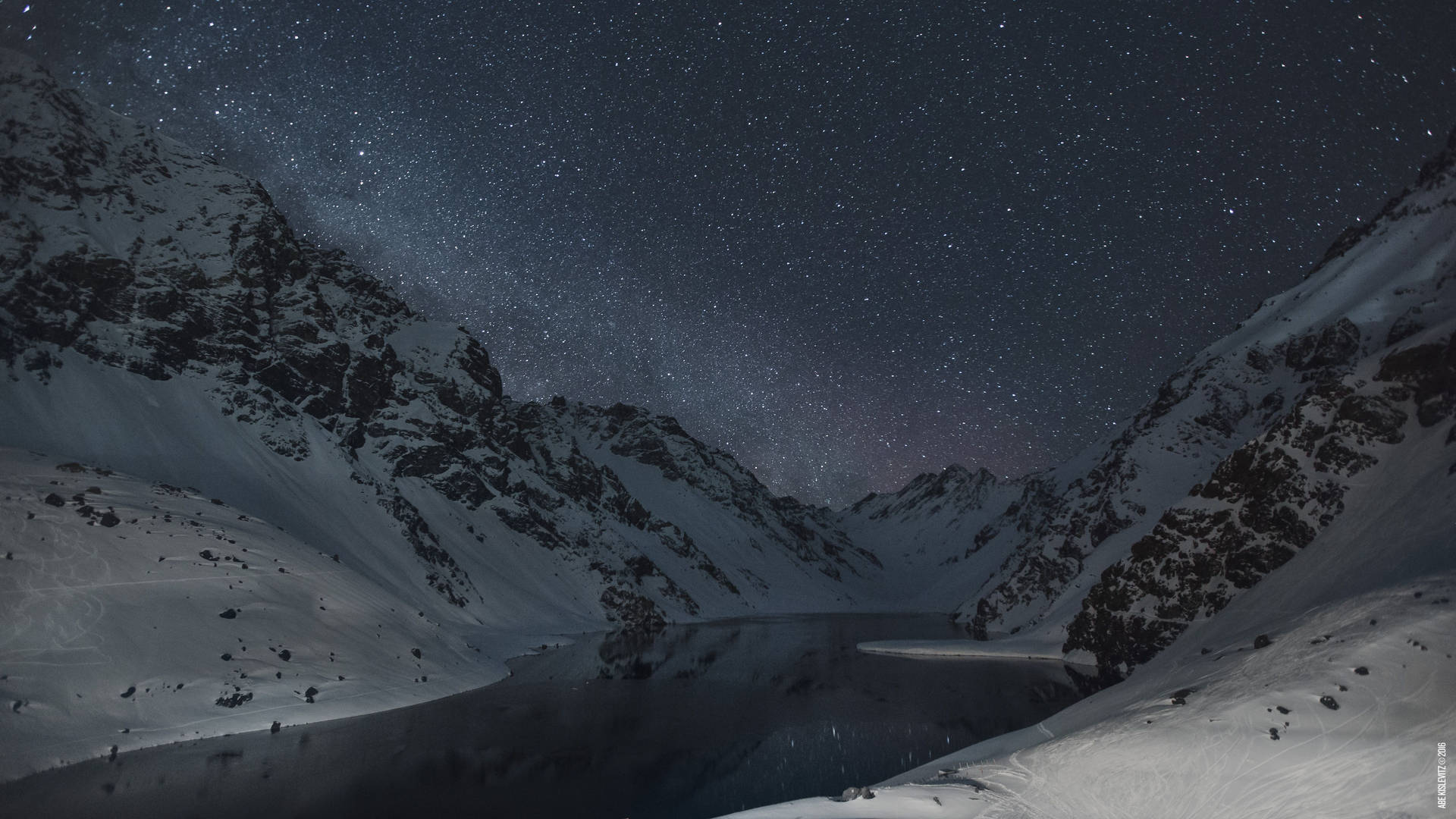 雪山環繞著寧靜湖泊中倒映的繁星夜空。
