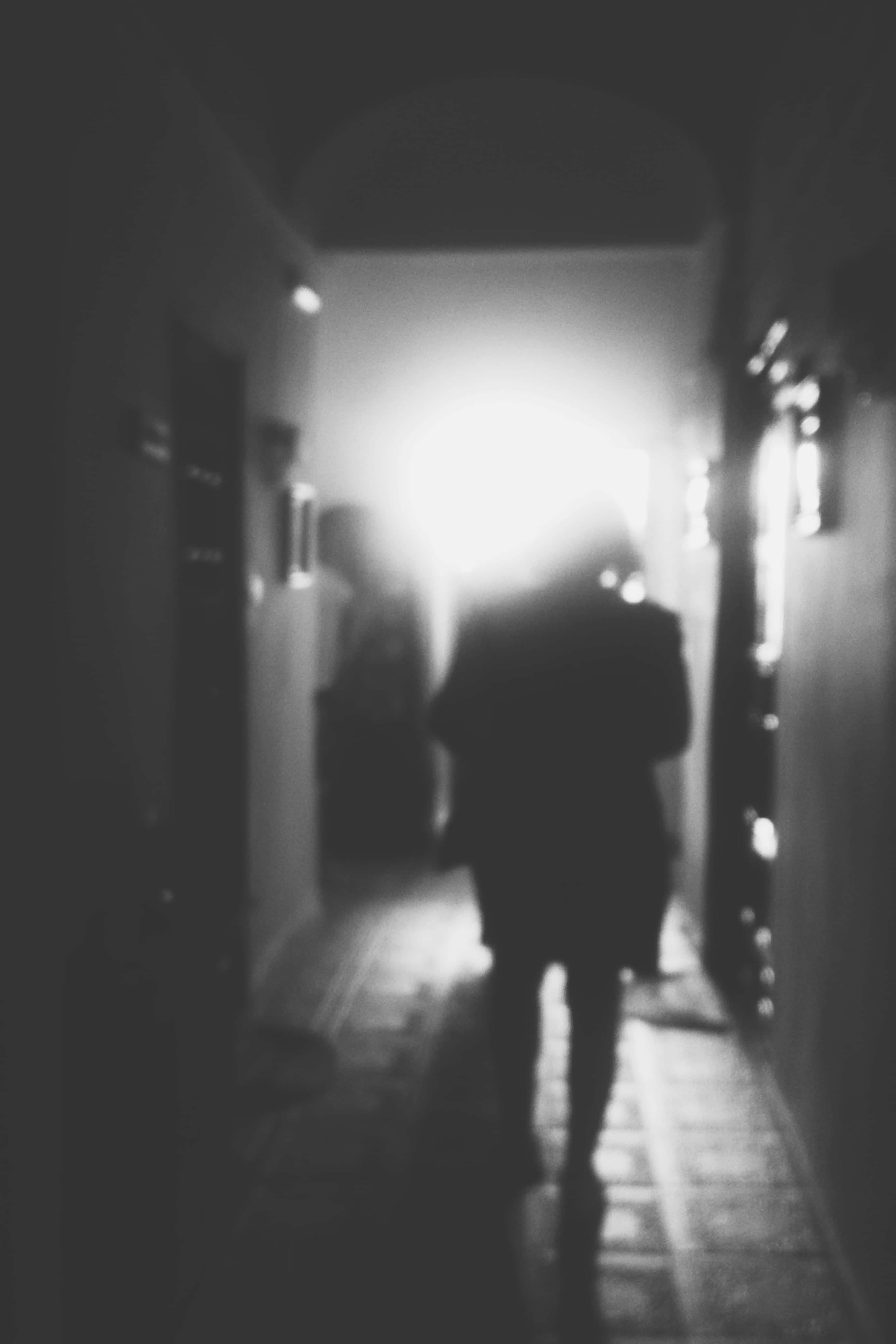 幽靈剪影鬼屋圖 壁紙 — 一個模糊嘅剪影喺昏暗嘅走廊行向盡頭嘅明亮光線。